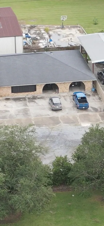 An aerial photo of a house with a grey SUV and a blue pickup truck parked in the driveway.
