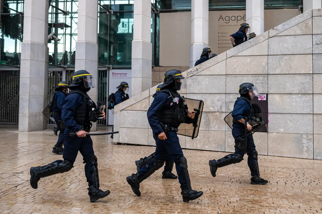 French CRS police officers in riot gear run at Saint-Charles train station during student protests in Marseille.