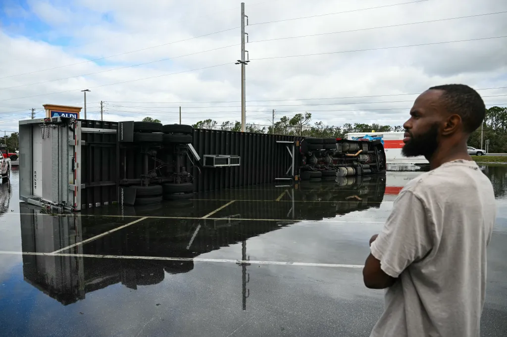A driver looks at his overturned truck in a flooded parking lot in Tiger Point, Florida.