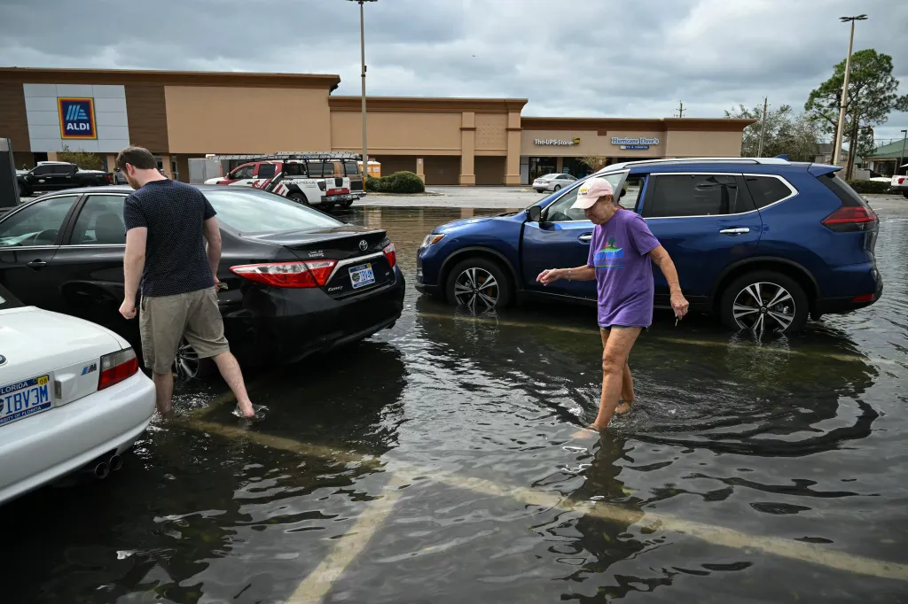 People walk through the water in a flooded shopping center parking lot in Tiger Point, Florida.