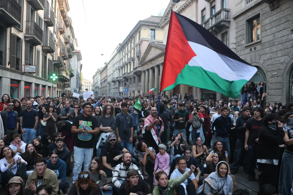 Protesters holding a Palestinian flag during a demonstration in a Milan street.