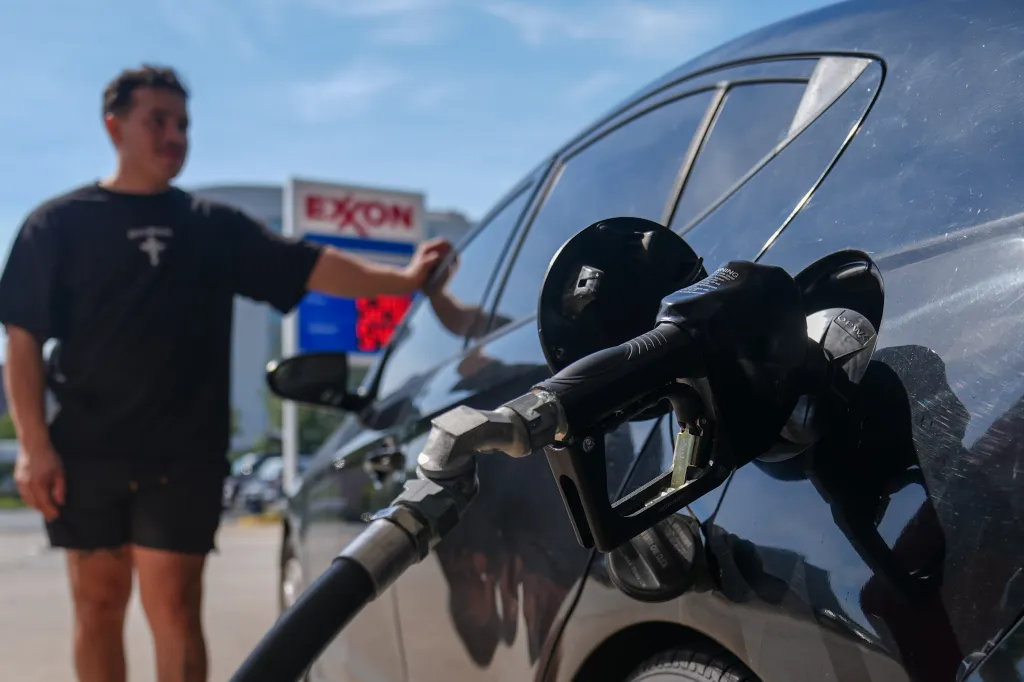 A man pumps gas into a vehicle at an Exxon gas station.