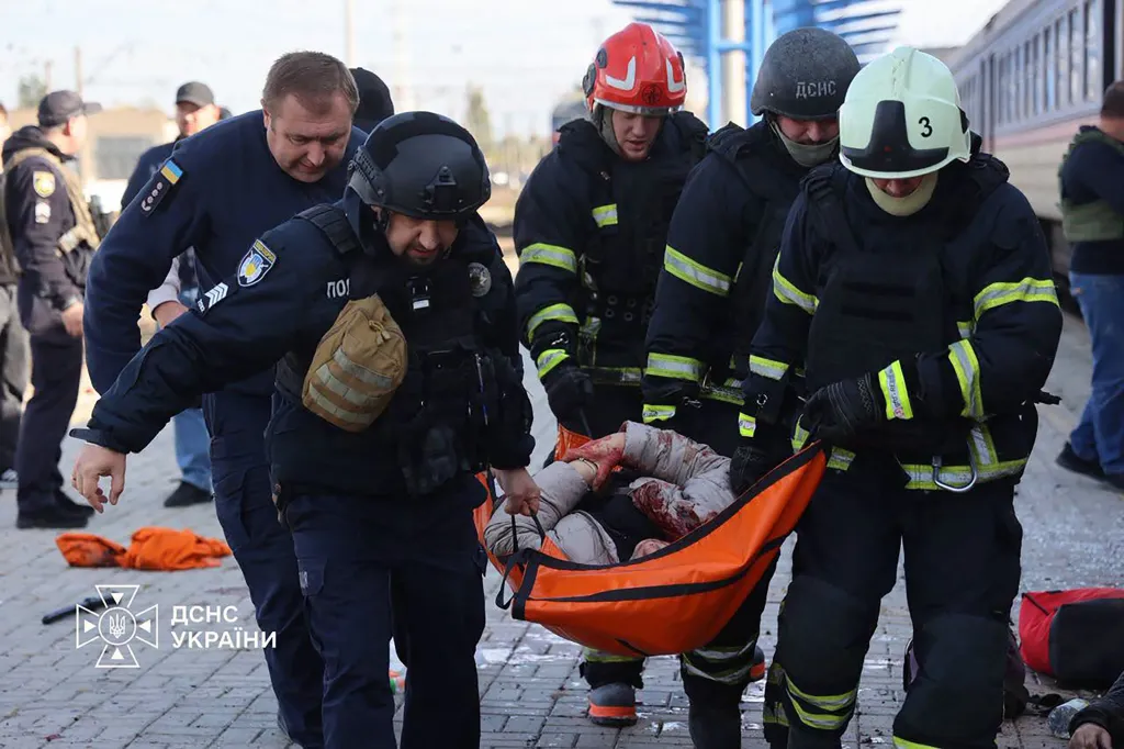 Ukrainian rescuers carry an injured person on a stretcher following an air attack on a railway station.