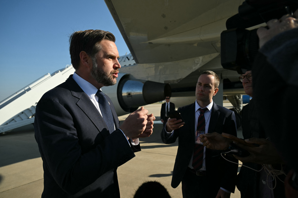 U.S. Vice President JD Vance speaks to reporters in front of an airplane.