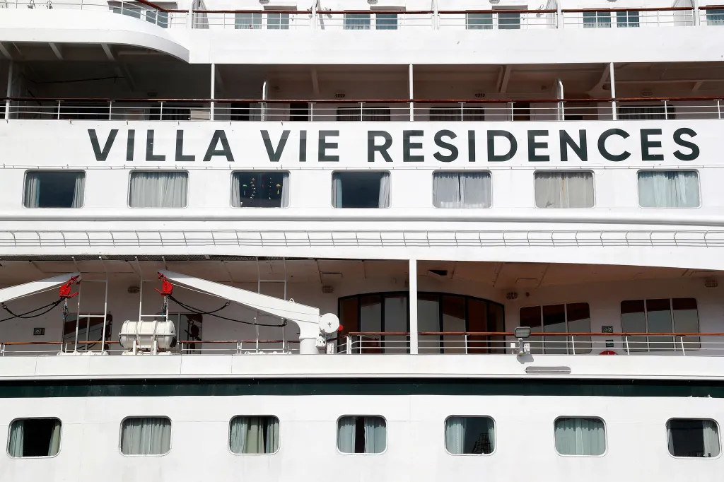 Close-up view of the white exterior of the Villa Vie Residences' cruise ship 'Odyssey', showing multiple decks with balconies and windows, docked at a port in Sihanoukville, Cambodia.
