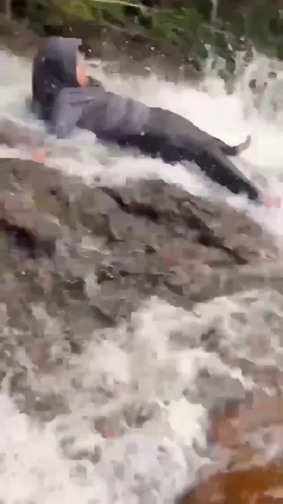 Windy Rahma Putri slips on wet rocks at an Indonesian waterfall.