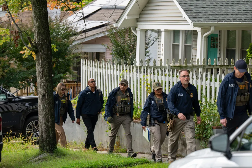 Homeland Security Investigations police walk past a house in Washington, DC.