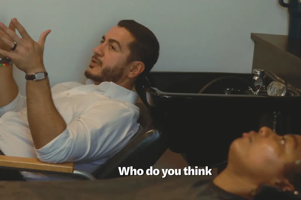 Abdul El-Sayed sitting in a salon chair, gesturing while talking to a person whose head is in the hair-washing sink.