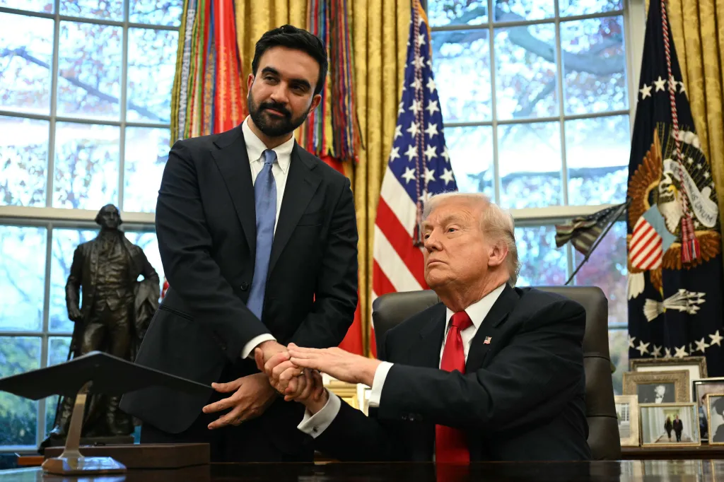 Donald Trump shakes hands with a man standing beside his desk in the Oval Office.
