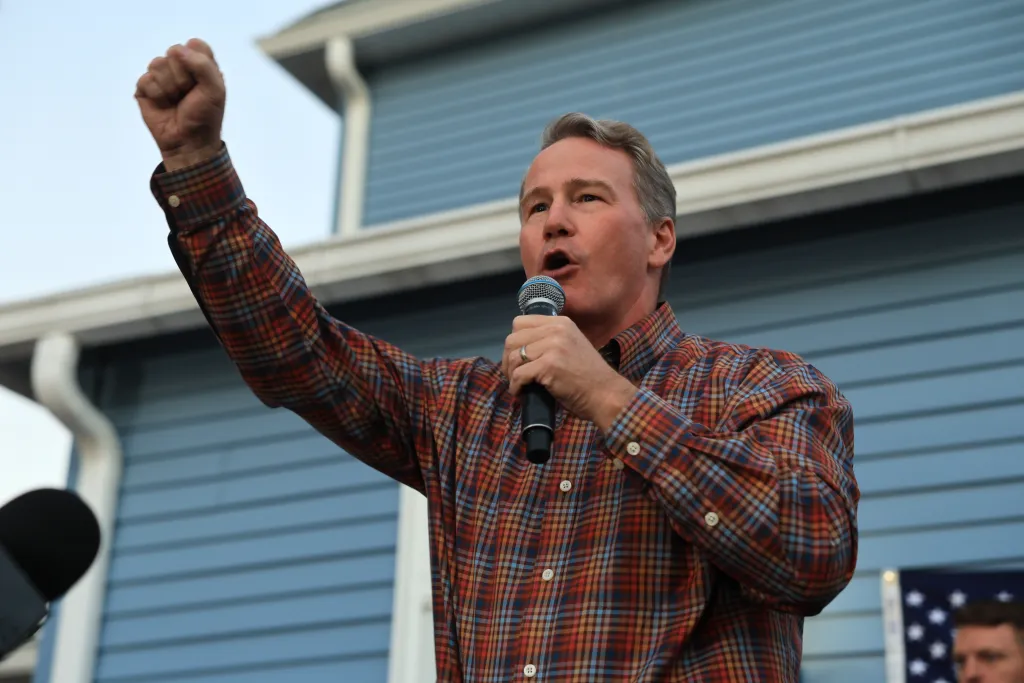 A man speaking into a microphone with his fist raised at the Circleville Pumpkin Show rally.
