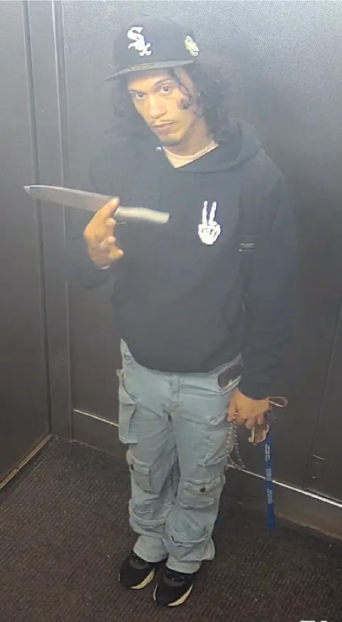A wanted poster photo of Angel Carrasco holding a knife.