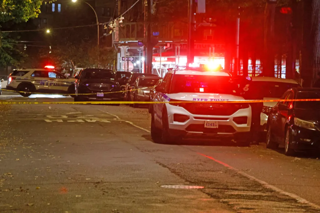 Police vehicles and yellow police tape cordon off a street where a 12-year-old girl was shot.