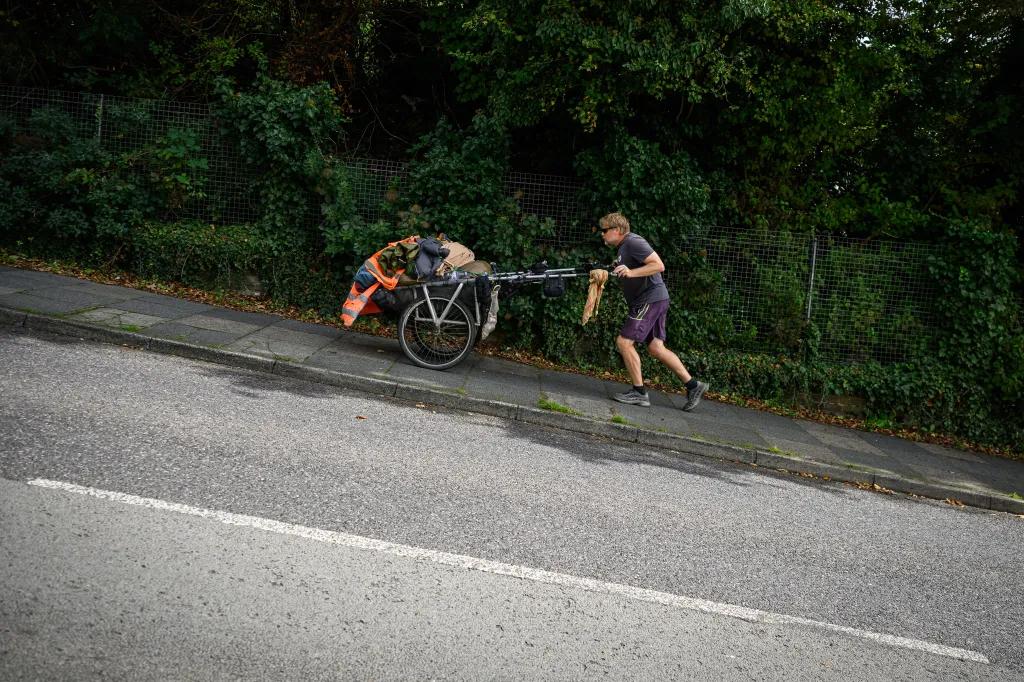 Global adventurer Karl Bushby tackles a steep incline on foot while pushing a cart loaded with gear in Dover, England.