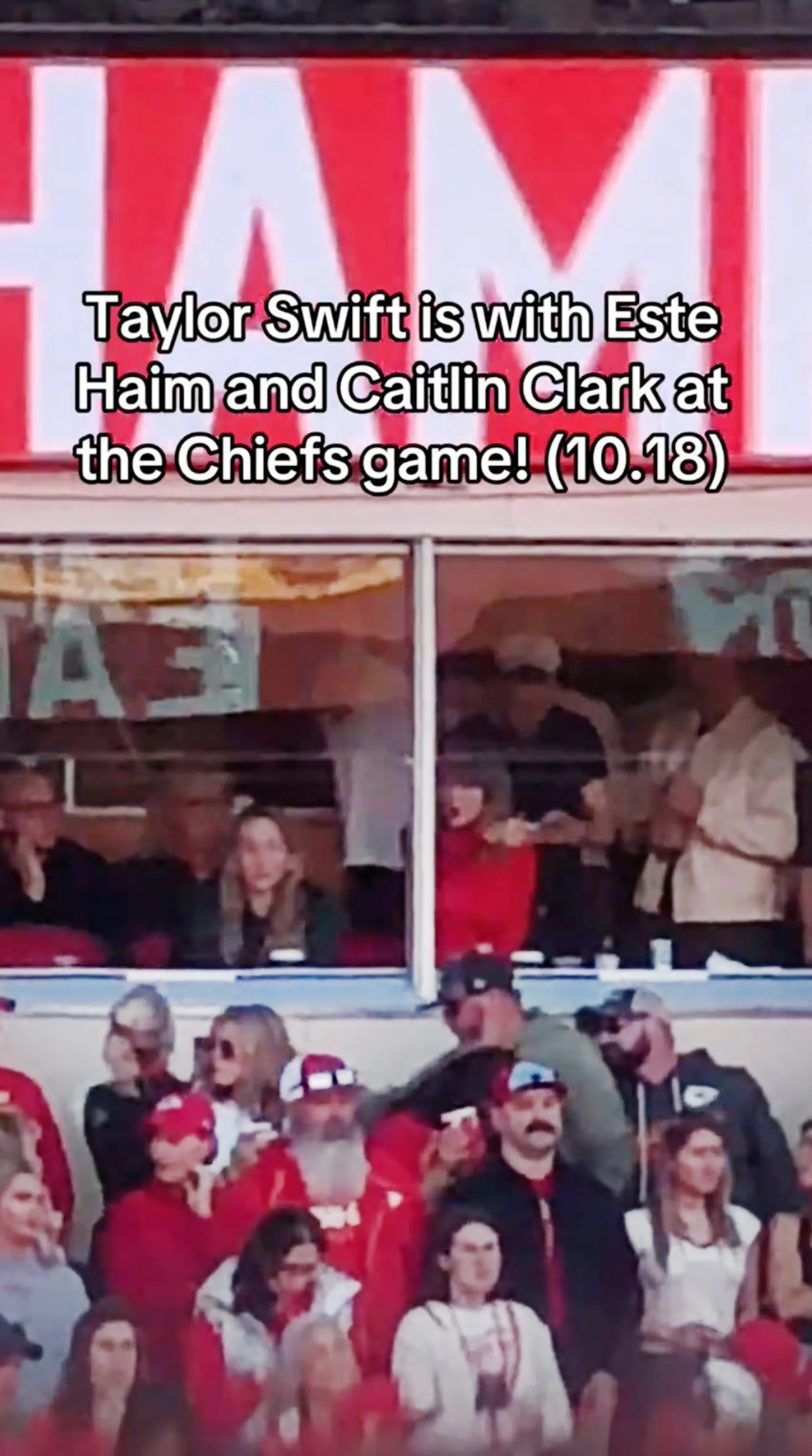 Taylor Swift gesturing at a fan from her VIP suite.