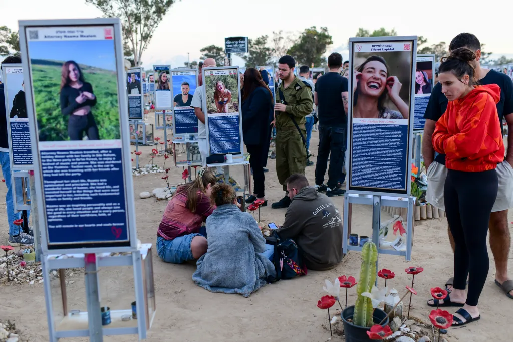Visitors gather around memorial portrait plaques at the Nova music festival memorial site.