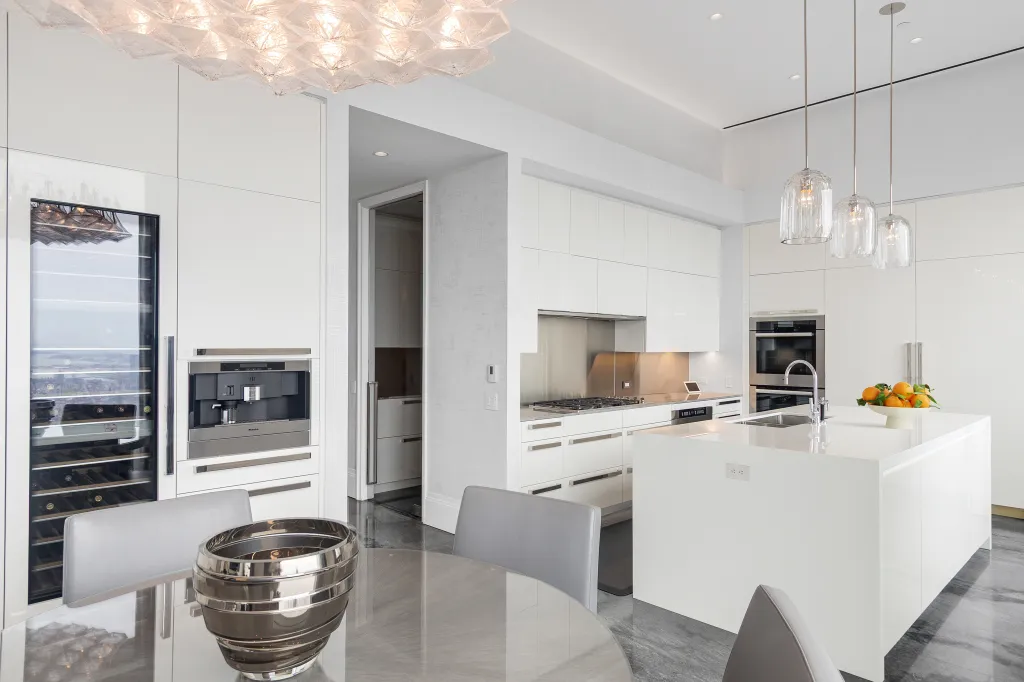 A chef's kitchen features a wine fridge and hanging lights.