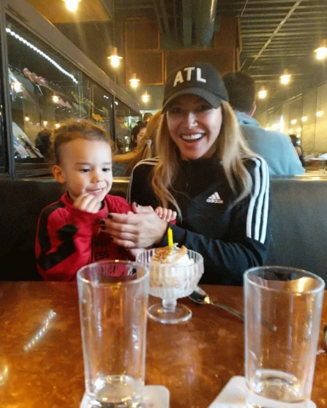 Naya Rivera celebrating with her son over a dessert with a single candle in a restaurant.