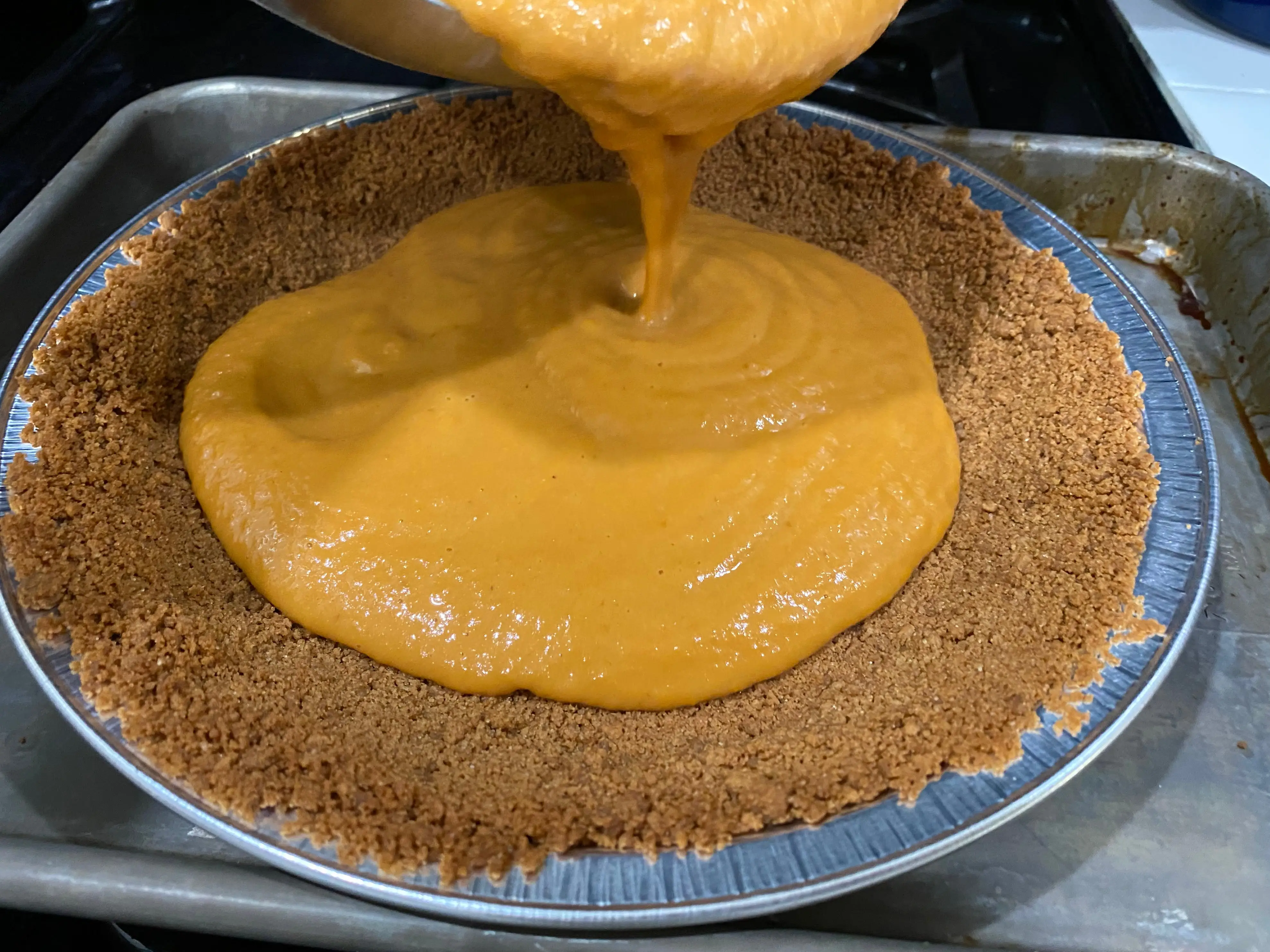 Alton Brown pumpkin pie filling being poured into crust
