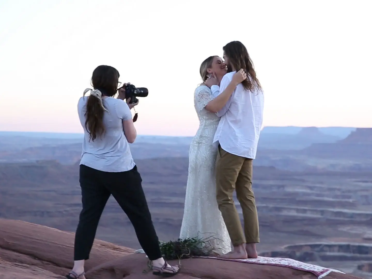 a wedding photographer getting a shot of the bride and groom standing in front of a vast landscape
