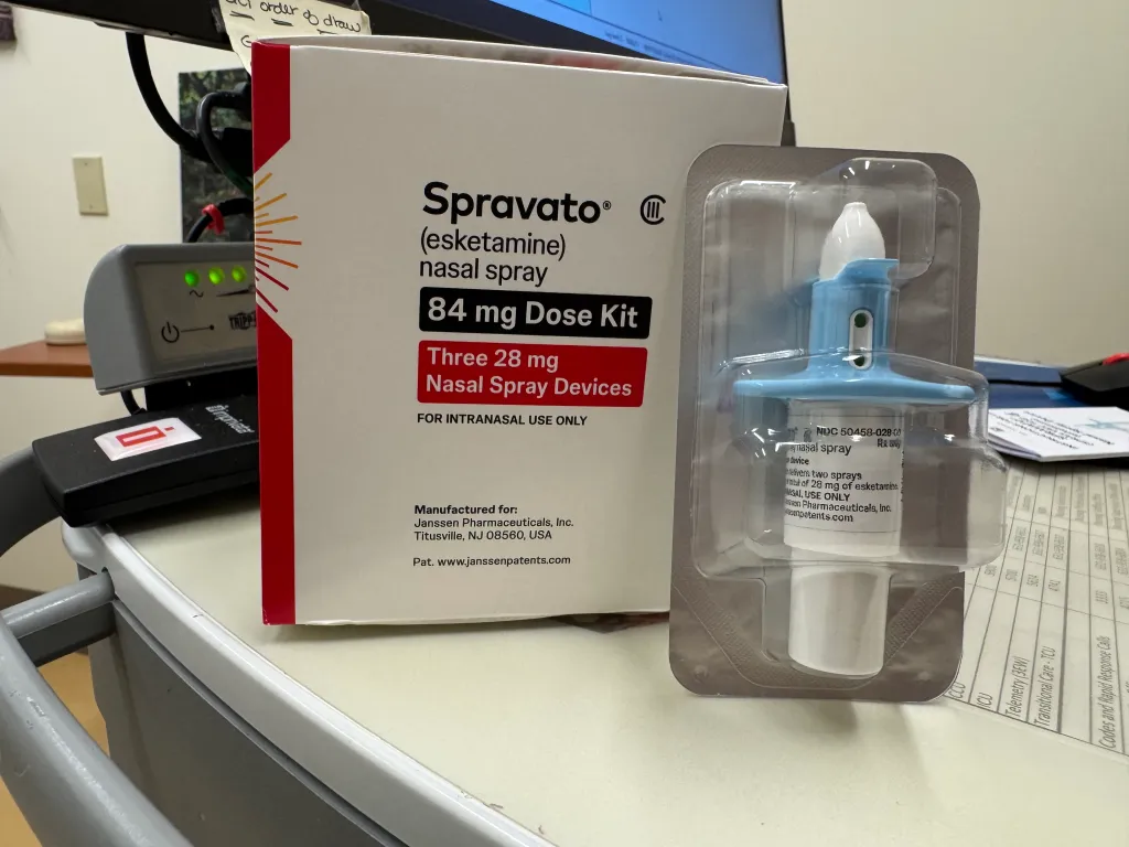 A box and sealed blister pack of Spravato (esketamine) nasal spray.