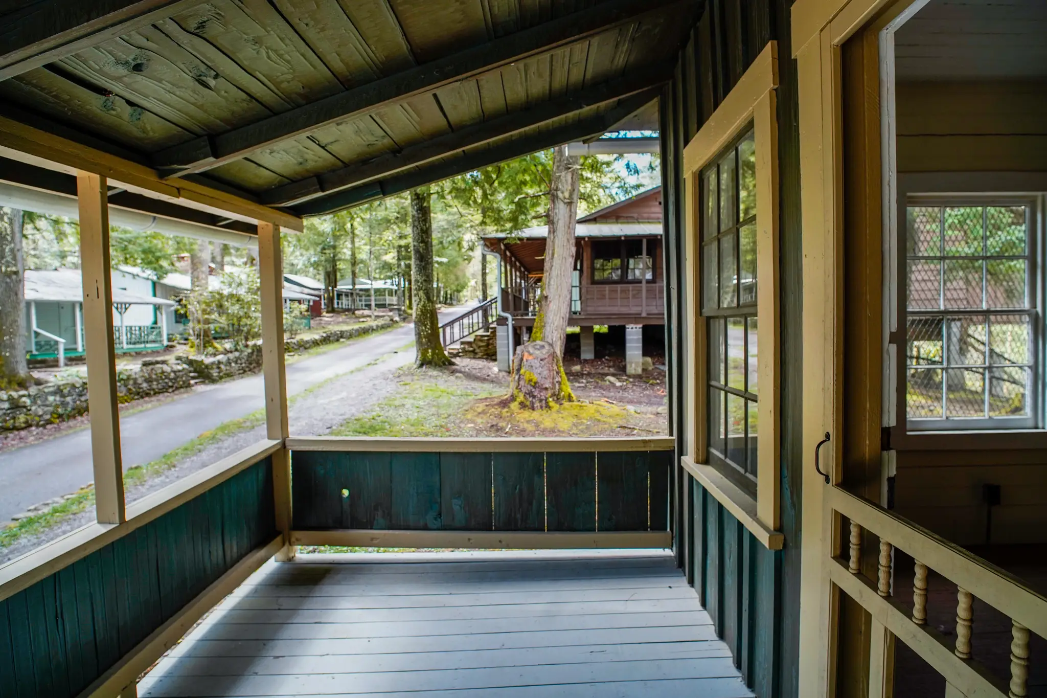 An emerald green porch with more cabins behind it