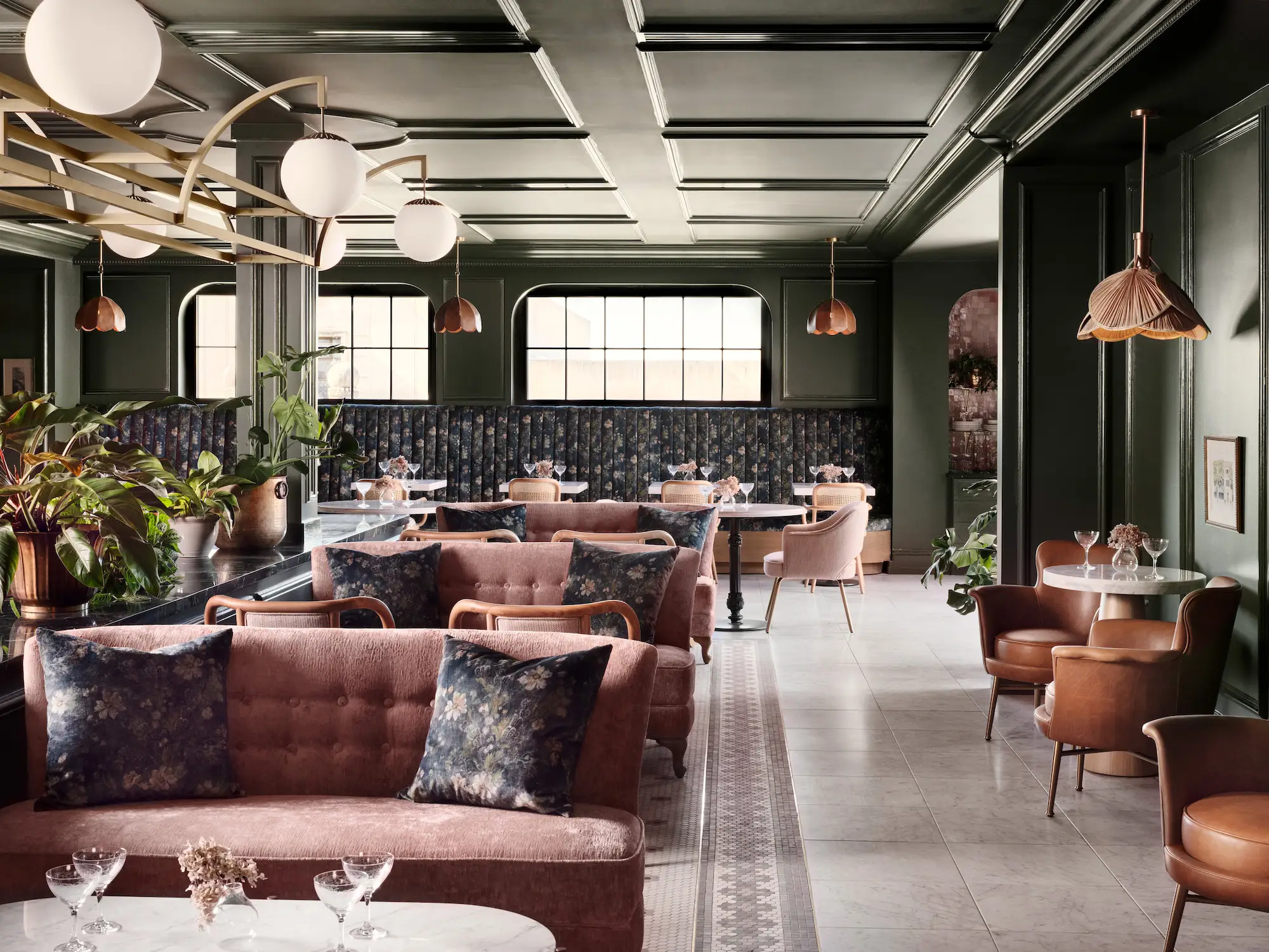 A cafe with pink sofas, floral booths, and green walls.