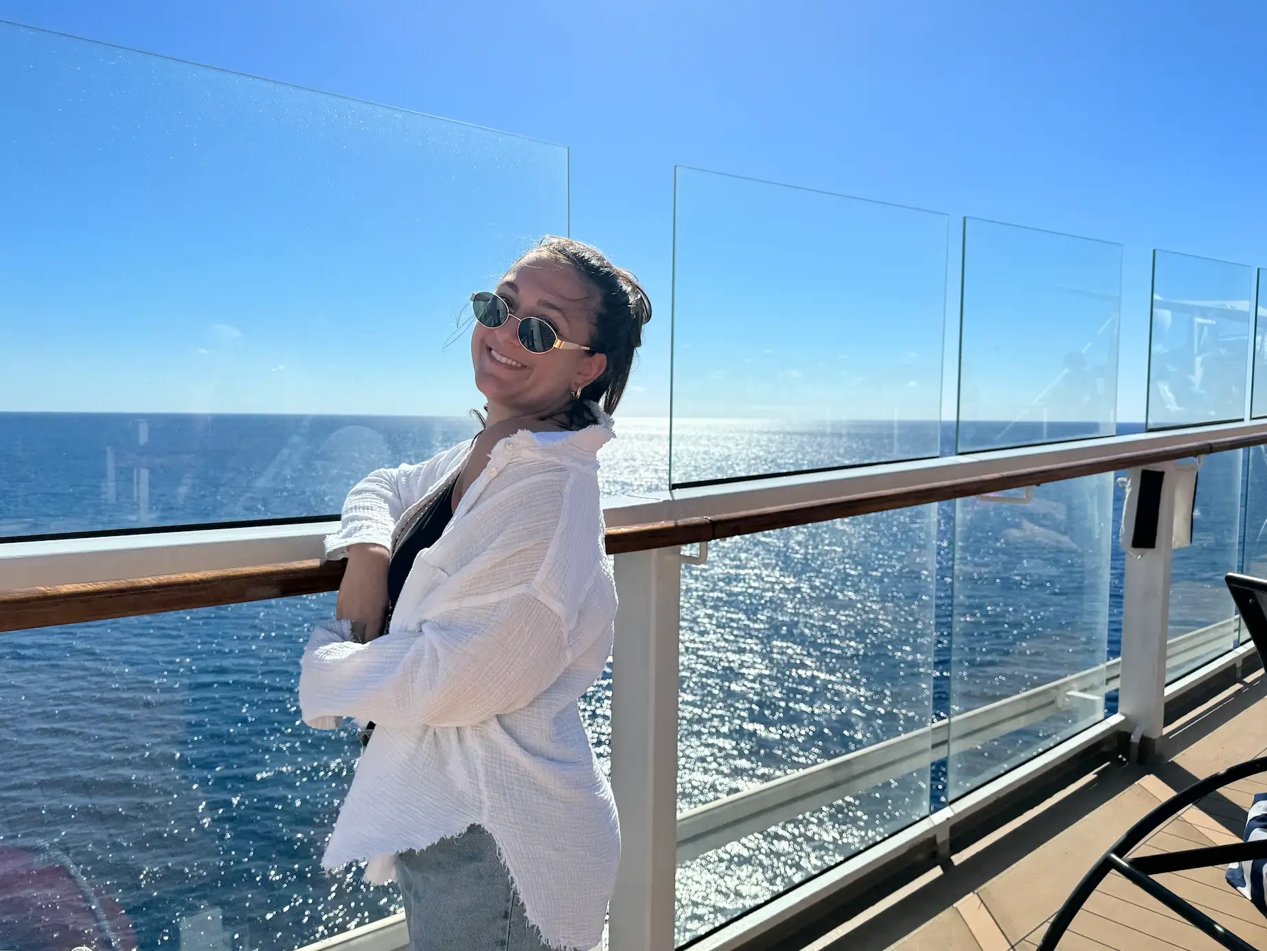 jordana posing on the deck of a cruise ship with blue waters and skies in the background