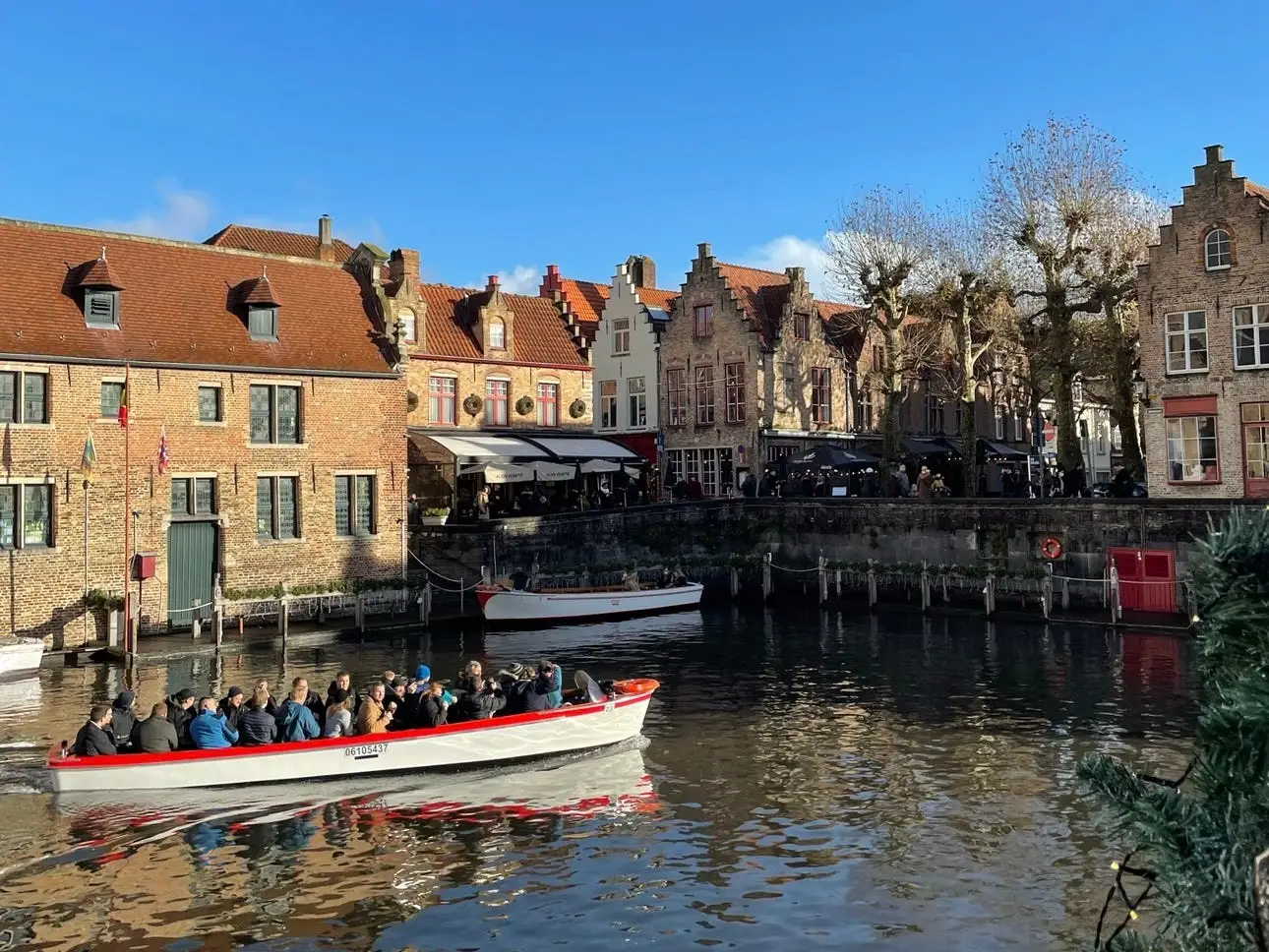 People riding in a boat on a river surrounded by charming brick buildings.