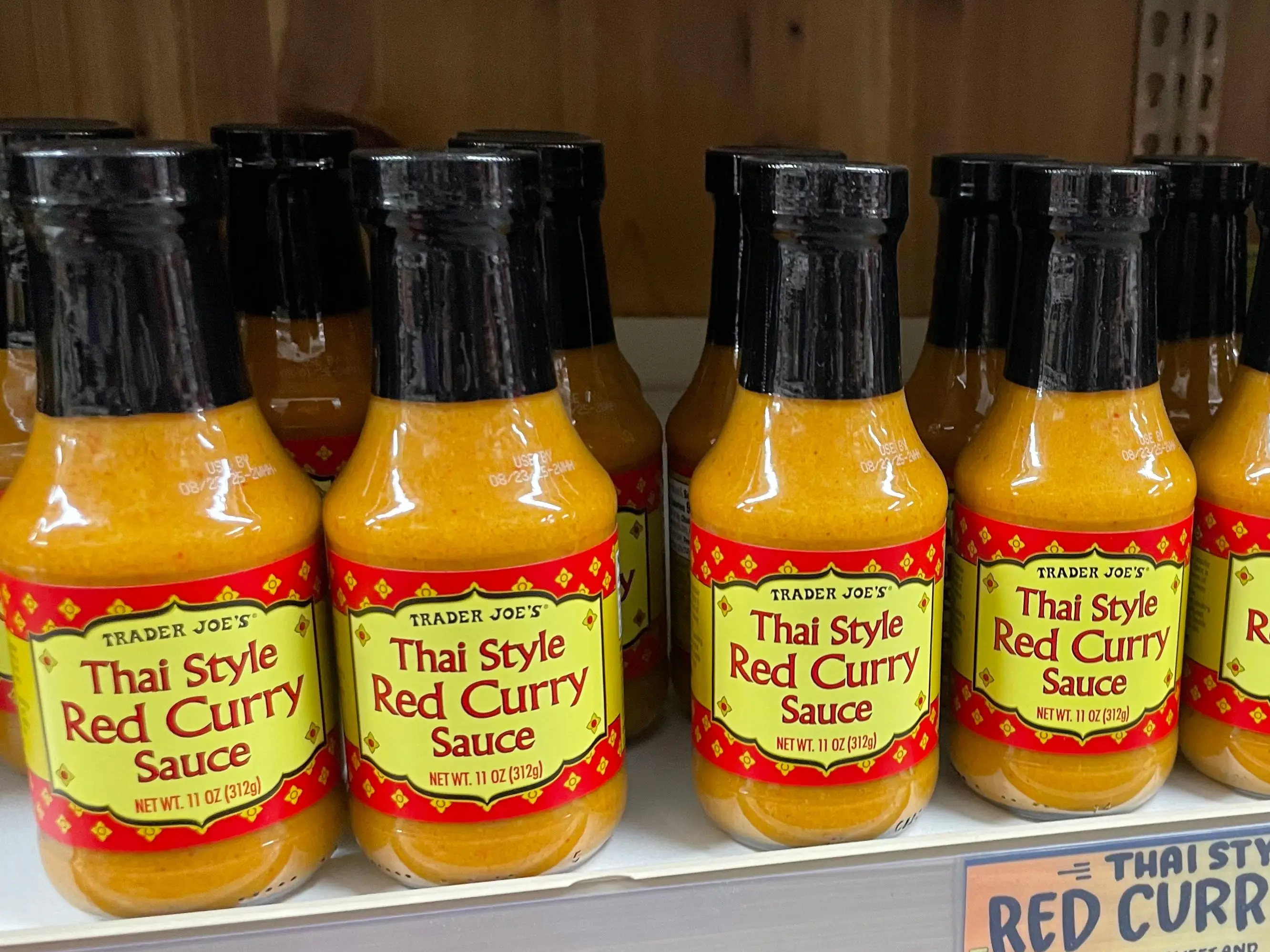 Bottles of Trader Joe's Thai-style red-curry sauce on a shelf.