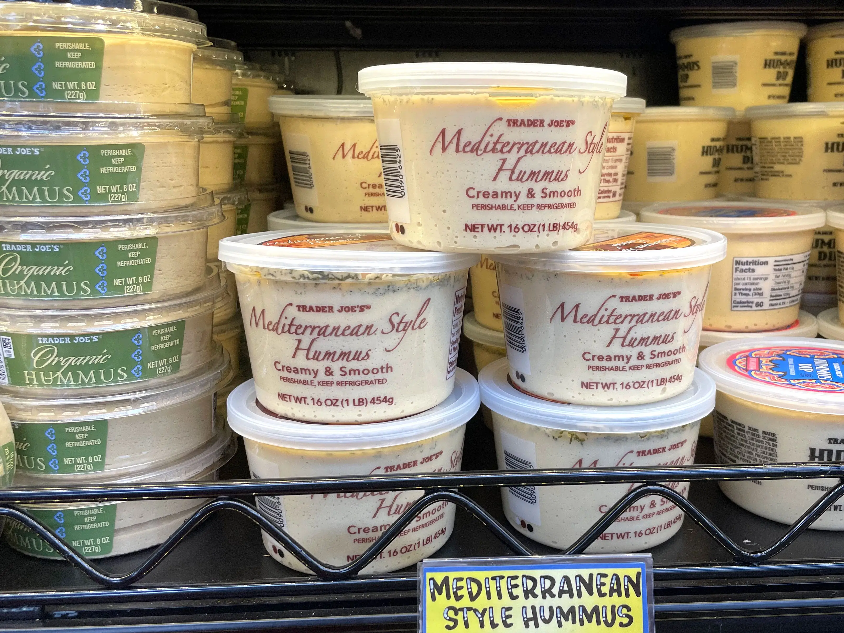 Stacks of different types of hummus on a shelf at Trader Joe's.
