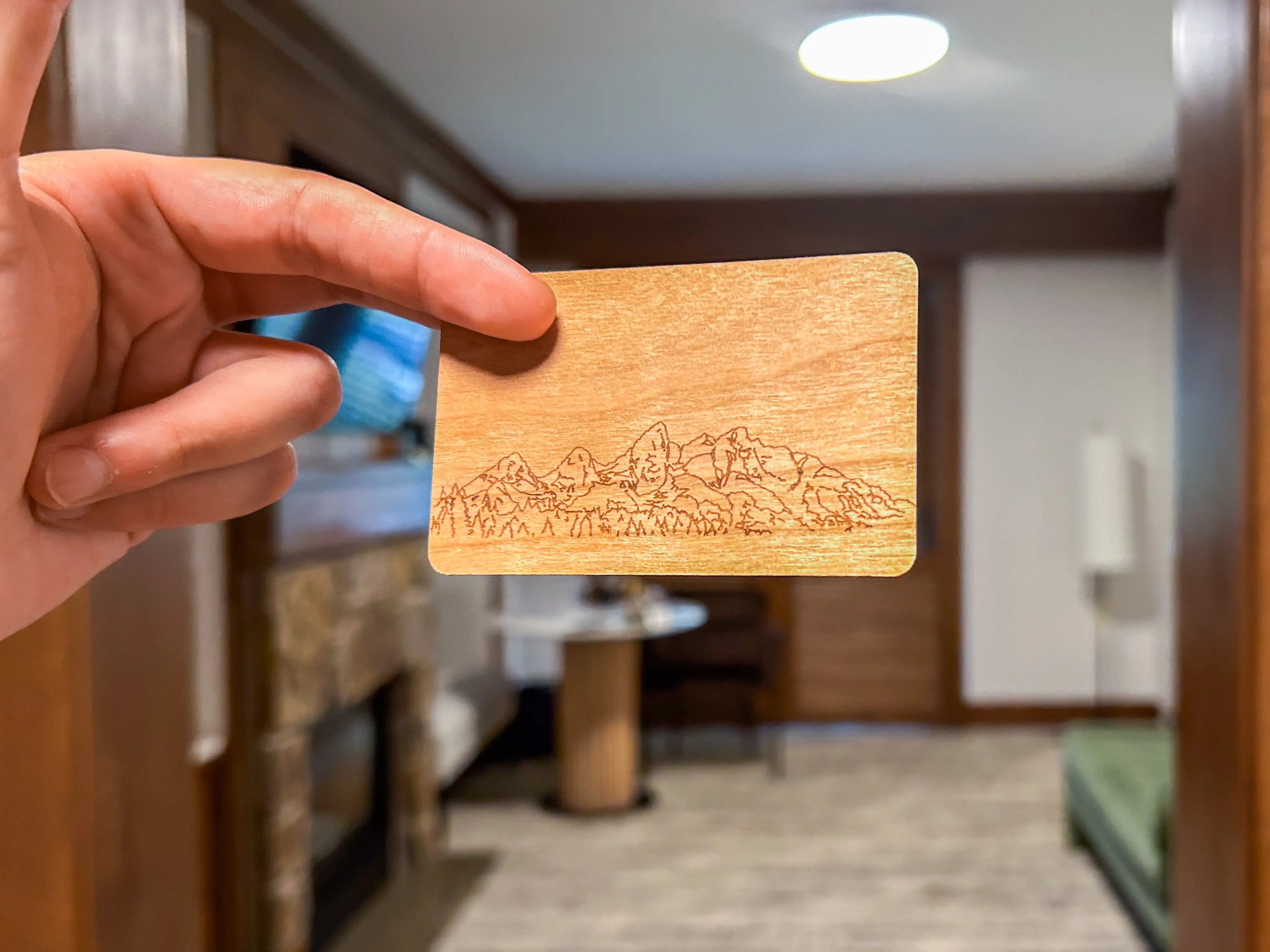A hand holds a wooden hotel key card