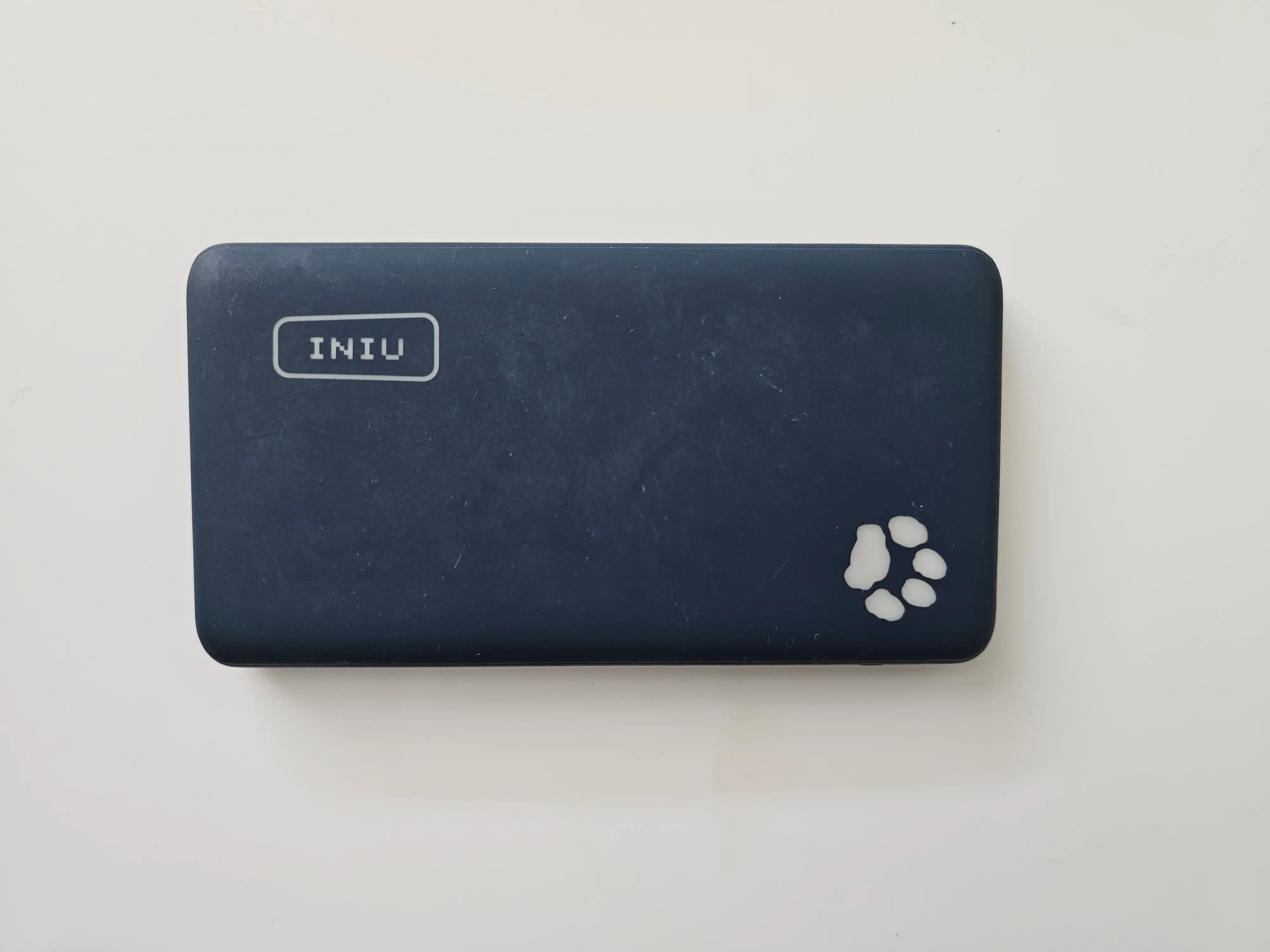 A blue portable charger from Iniu with a dog-paw print on it.