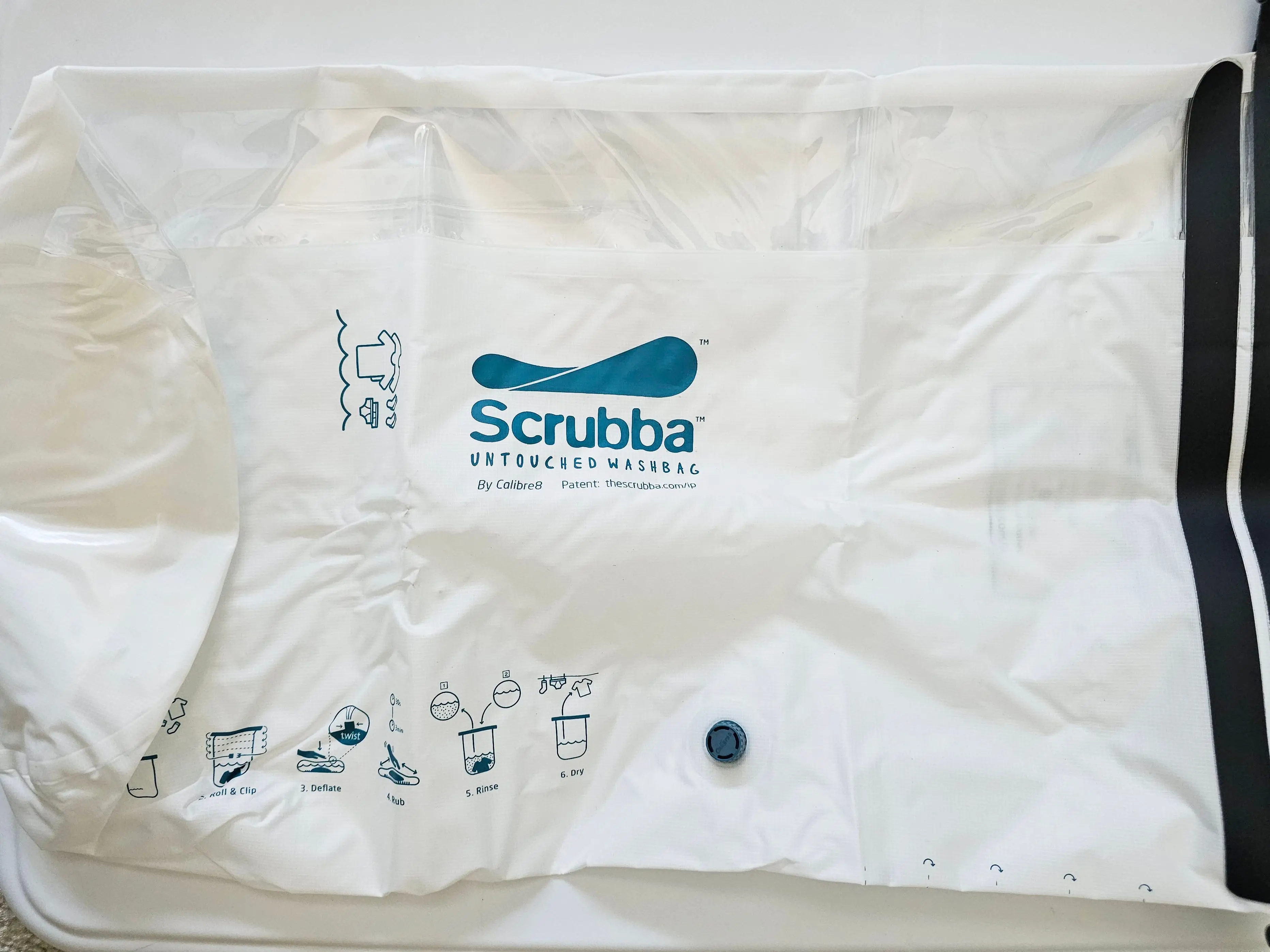 A white washbag from Scrubba with directions on how to do laundry on the bag in blue ink.