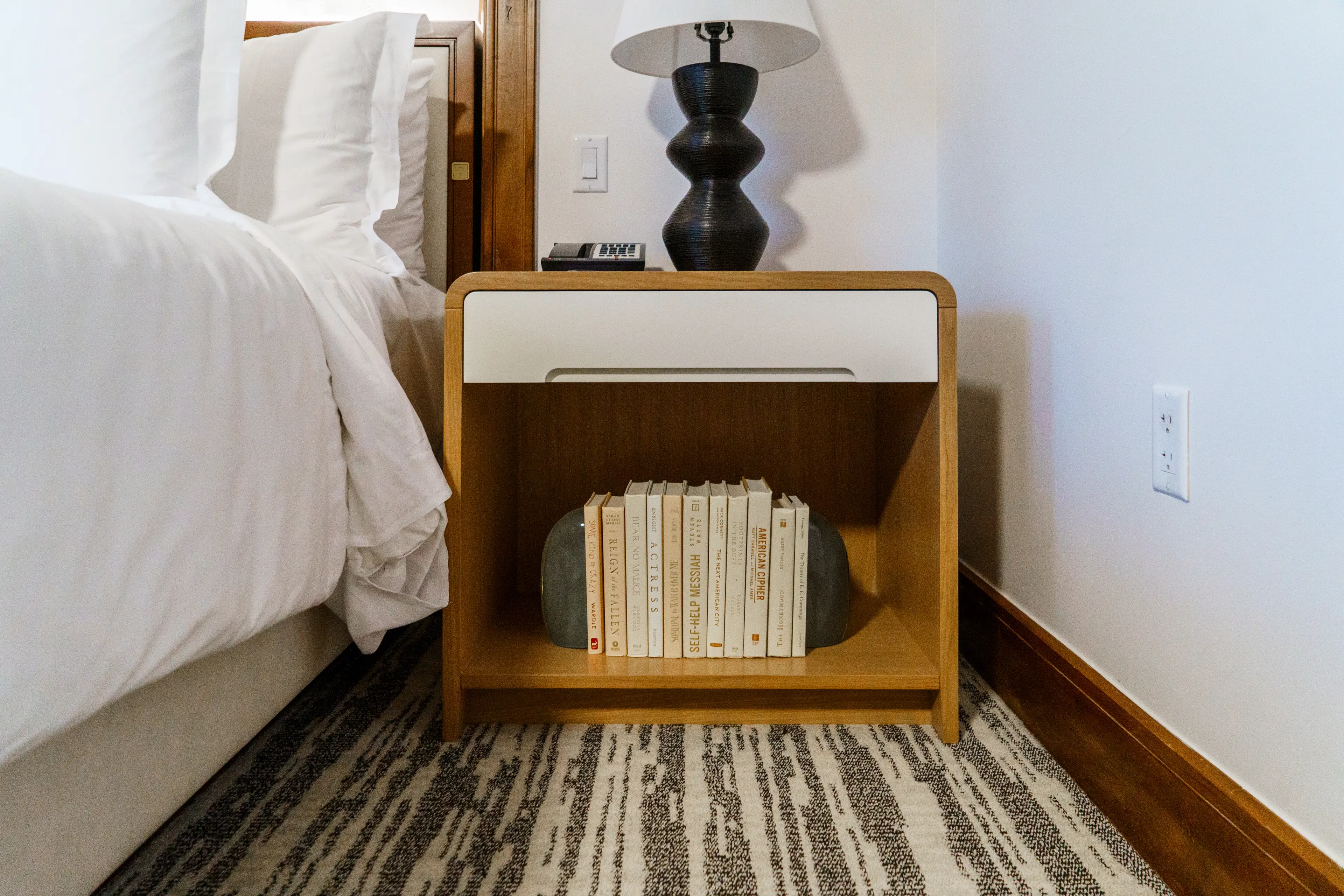 A close up of the nightstand shows a bottom shelf with books on it