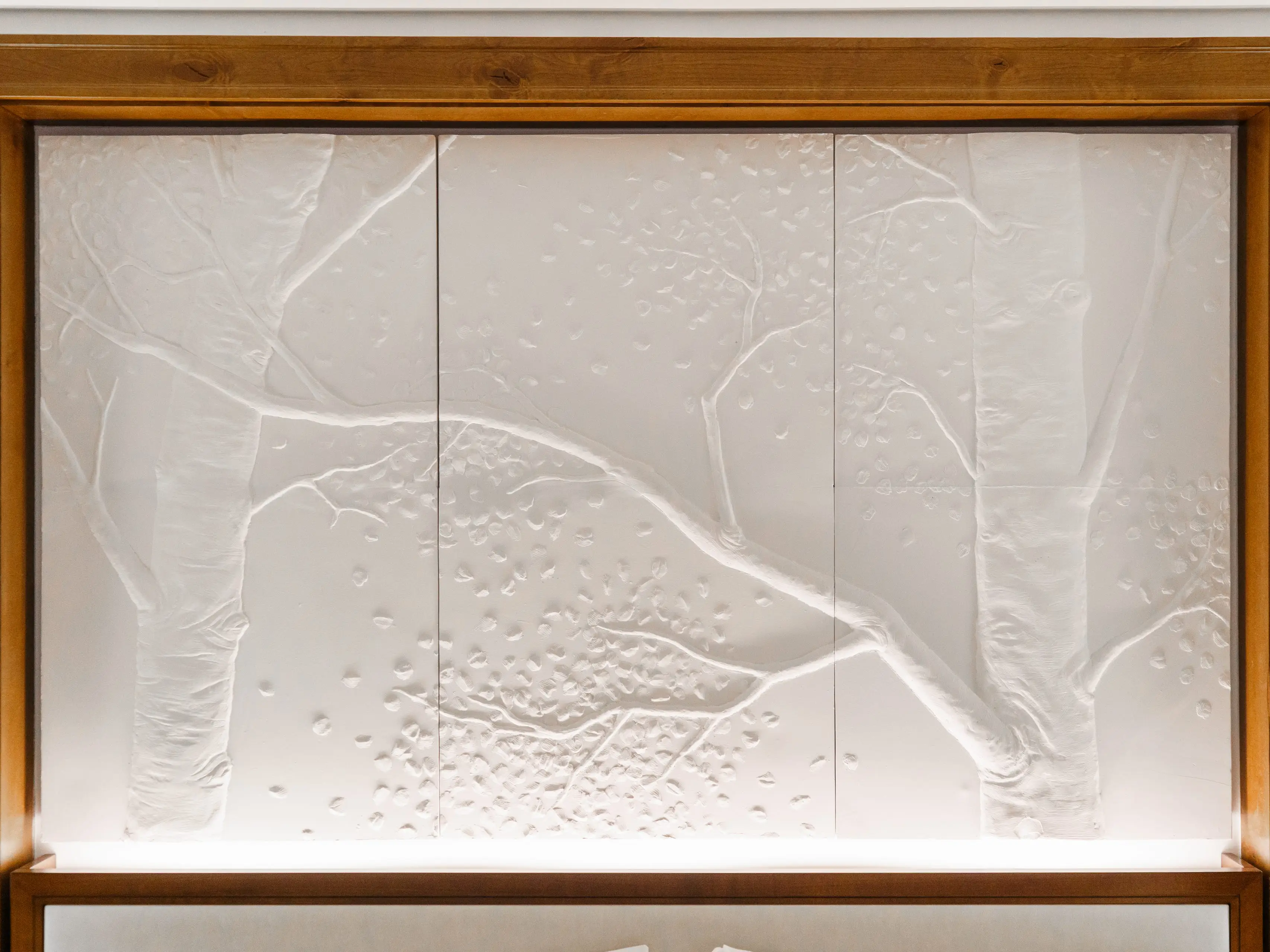 A close up of a wood-framed white headboard with carvings of trees on is