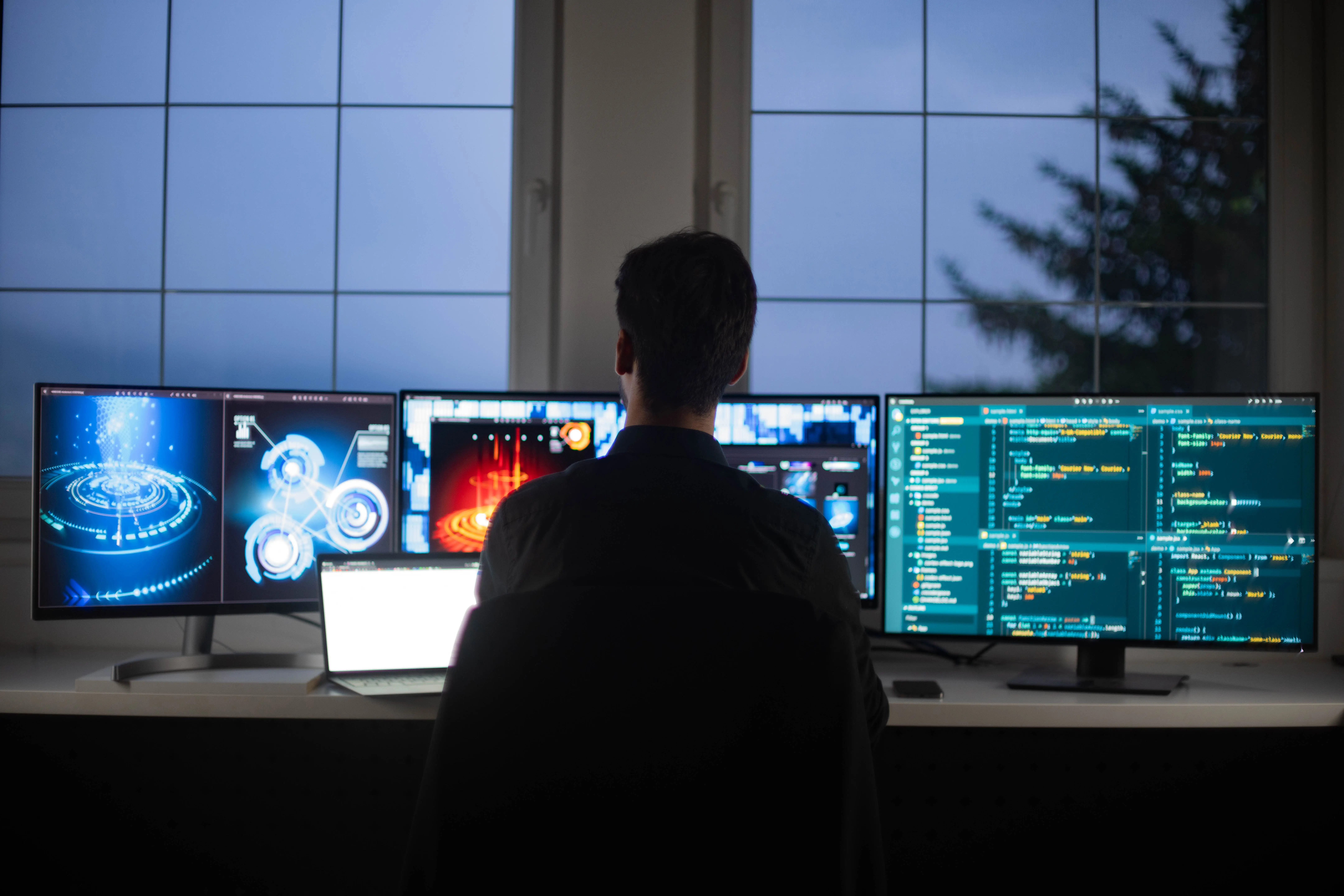A cybersecurity worker sits behind multiple screens.