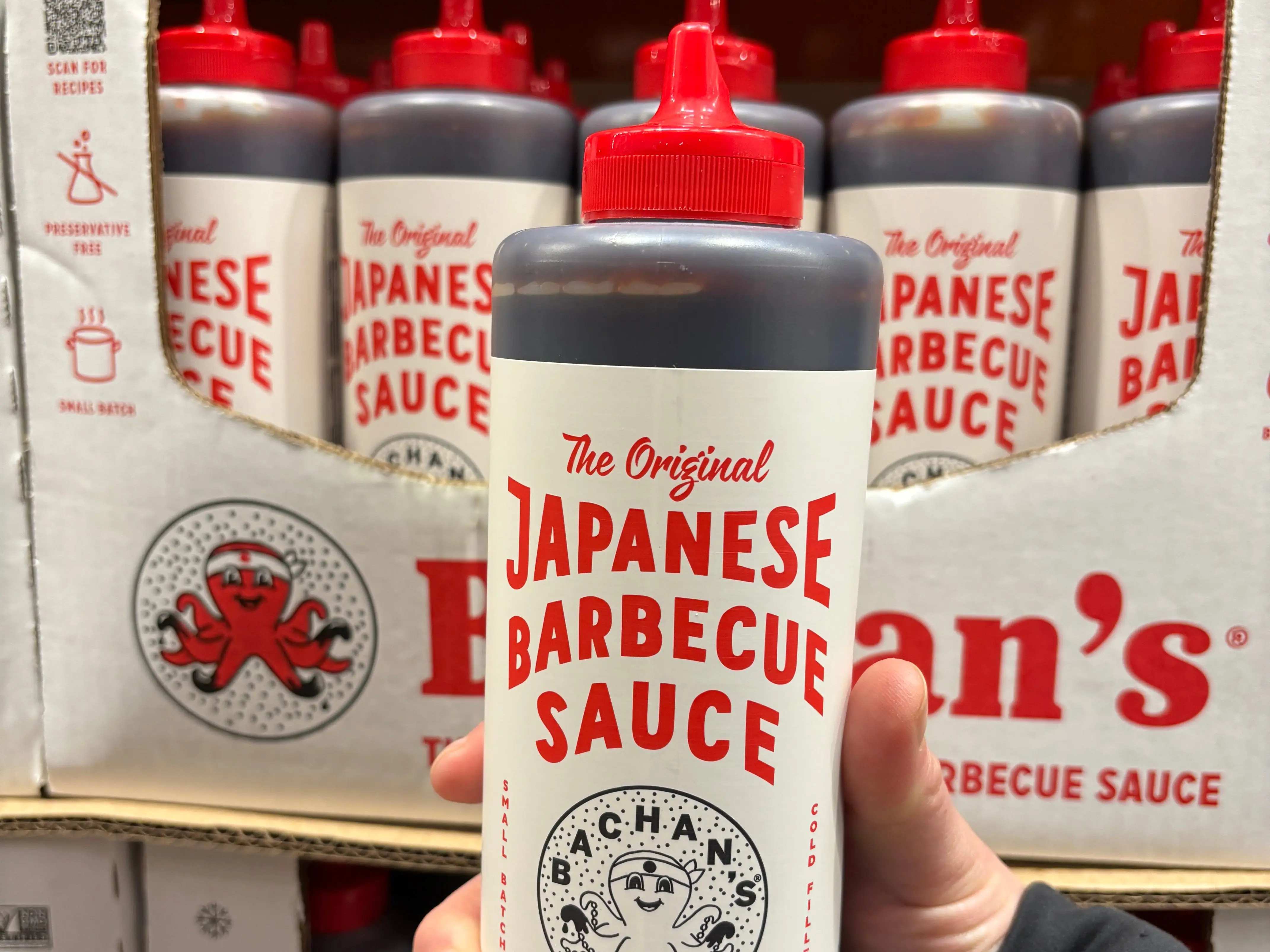 A hand holding a bottle of Bachan's Japanese barbecue sauce.