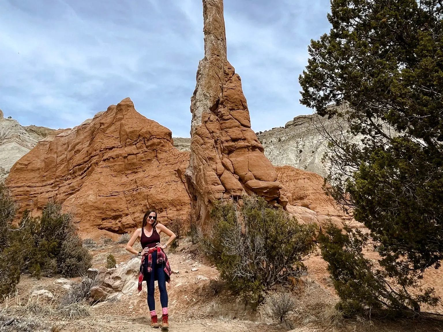 Emily stands next to a tall, thin red rock formation.