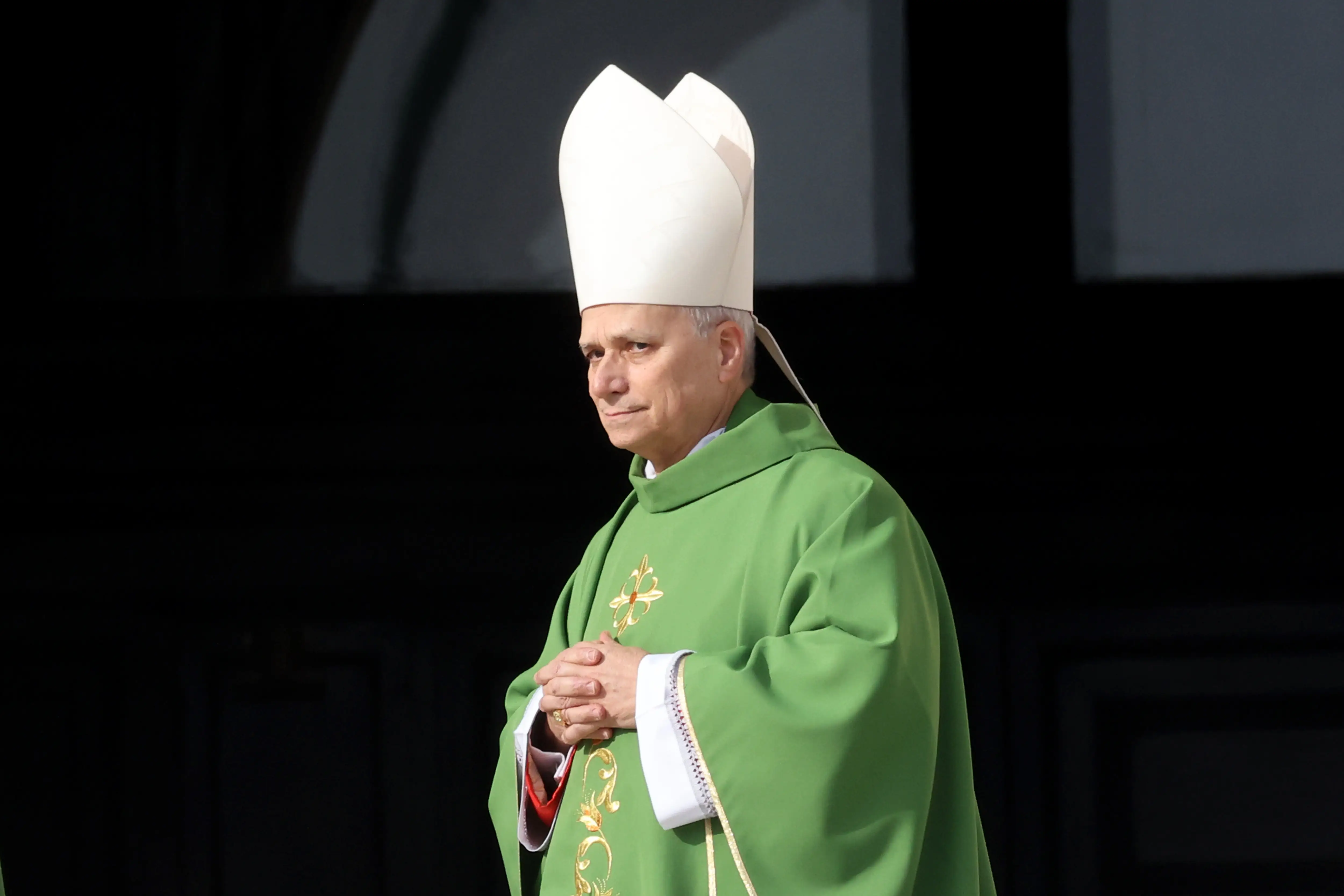 Pope Leo XIV in green and tall white hat holding his hands together
