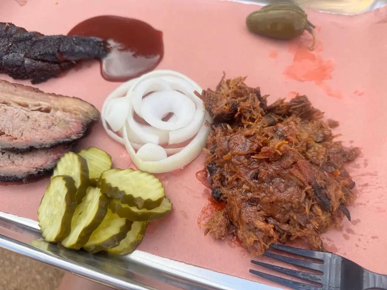 Brisket, pulled pork, onions, pickles on pink paper on tray