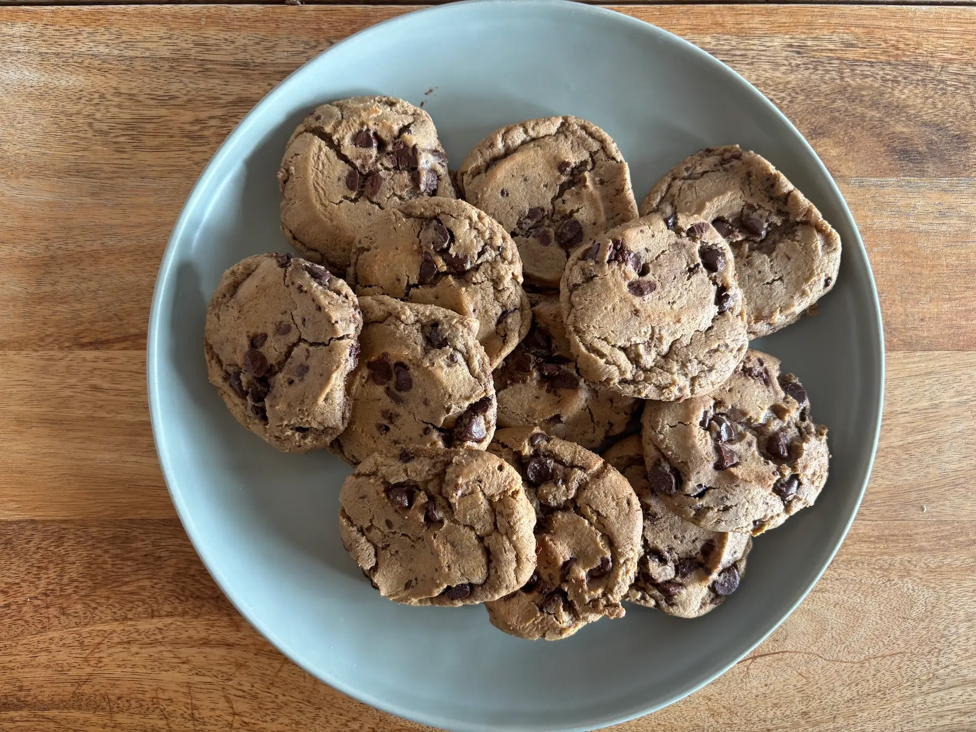 A plate of chocolate chip cookies on a wooden table.