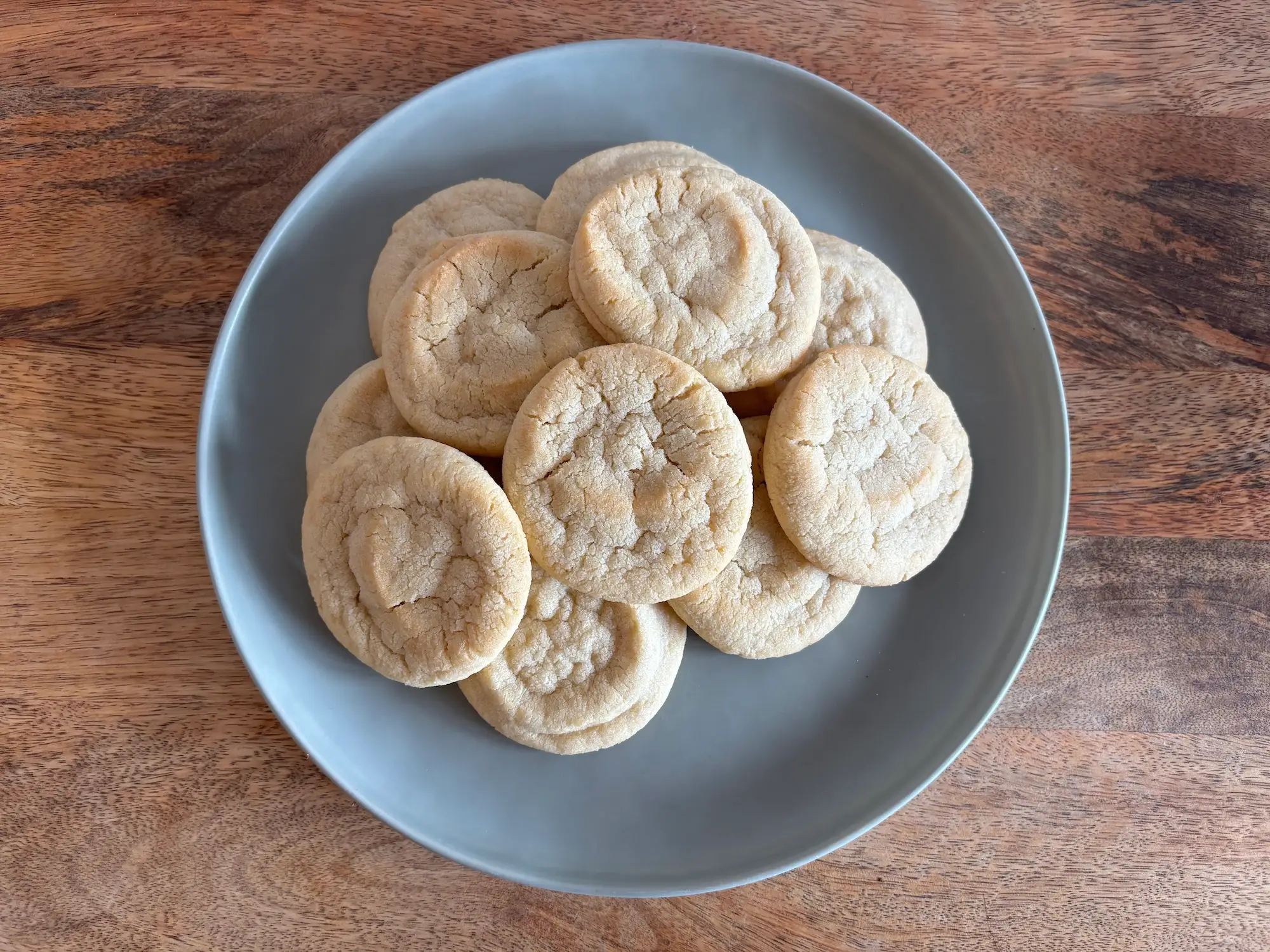 A plate full of sugar cookies on a wooden table.