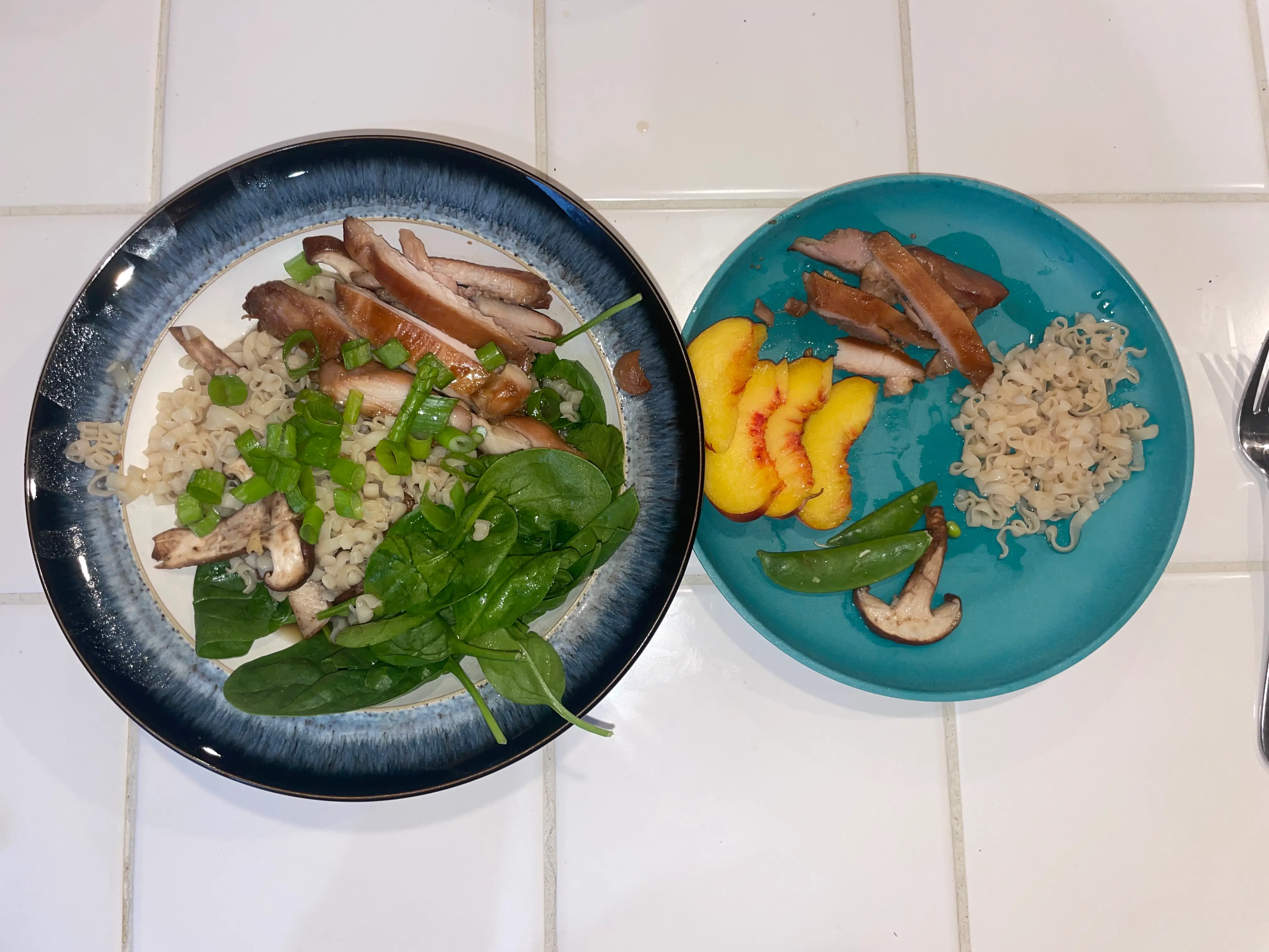 Ramen in a bowl next to bowl with ramen noddles, fruit, meat