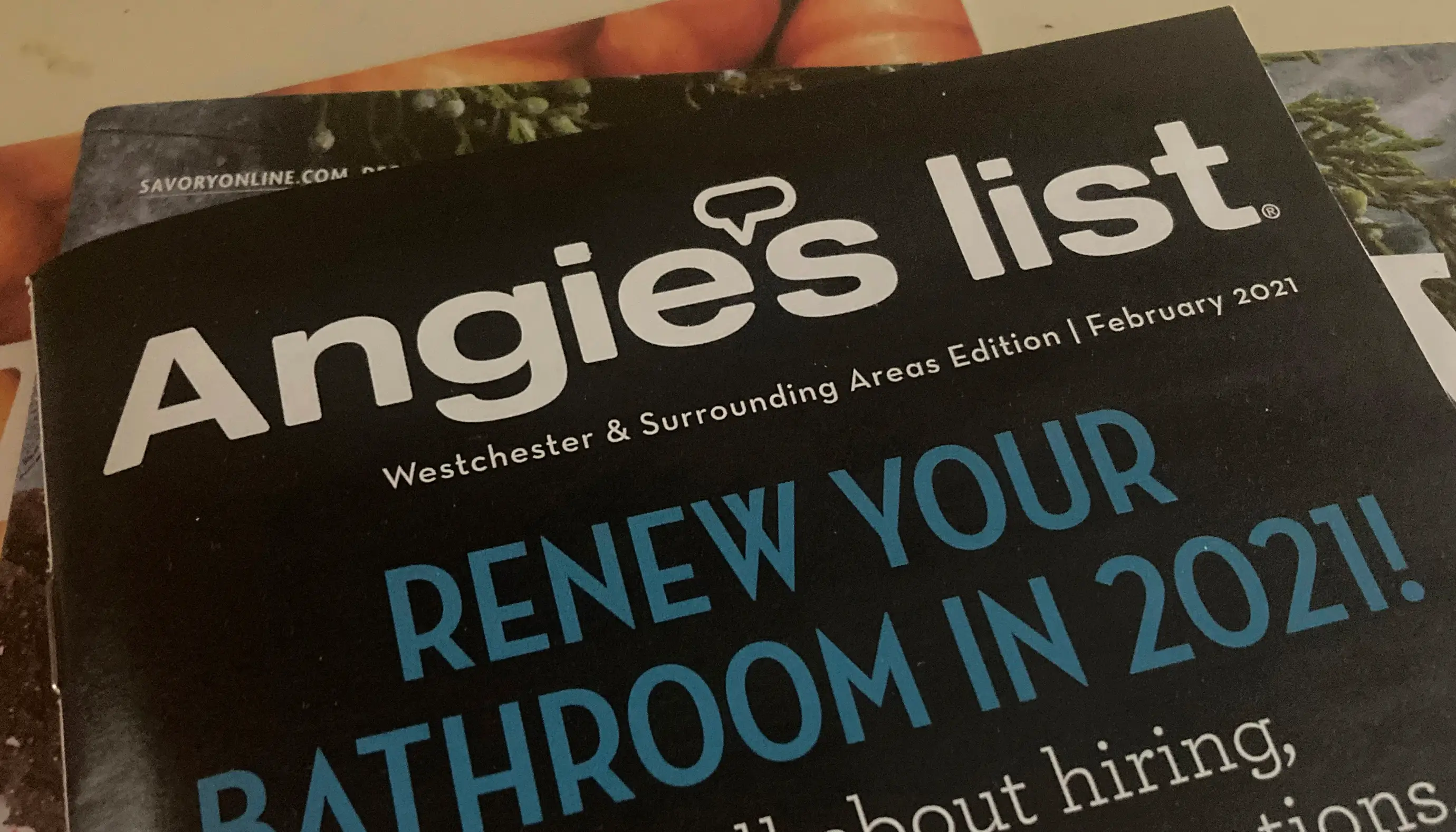 An Angie's List printed publication for 2021 sits on a stack of magazines and other printed materials.