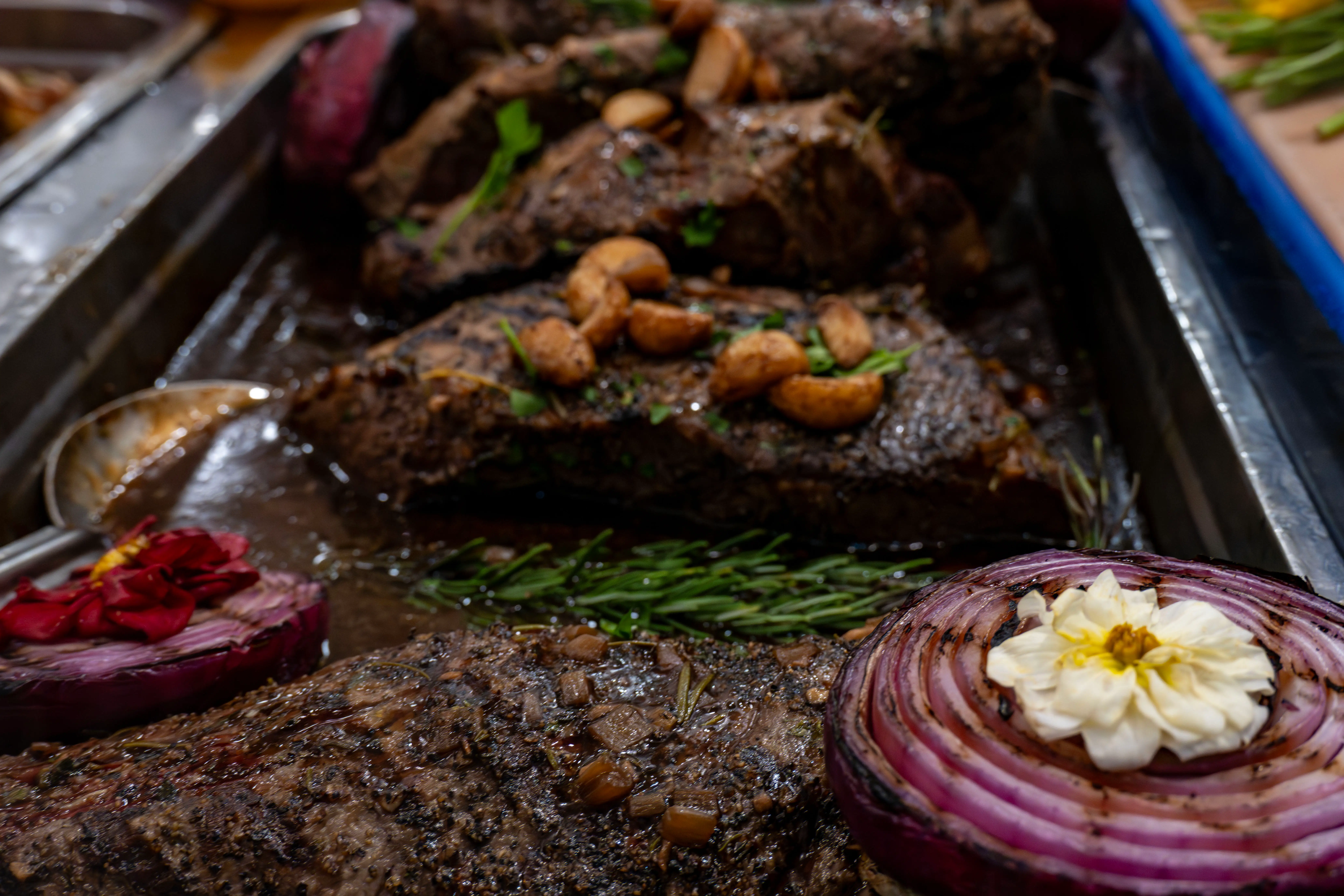 Steak in tray with cooked onions, garlic