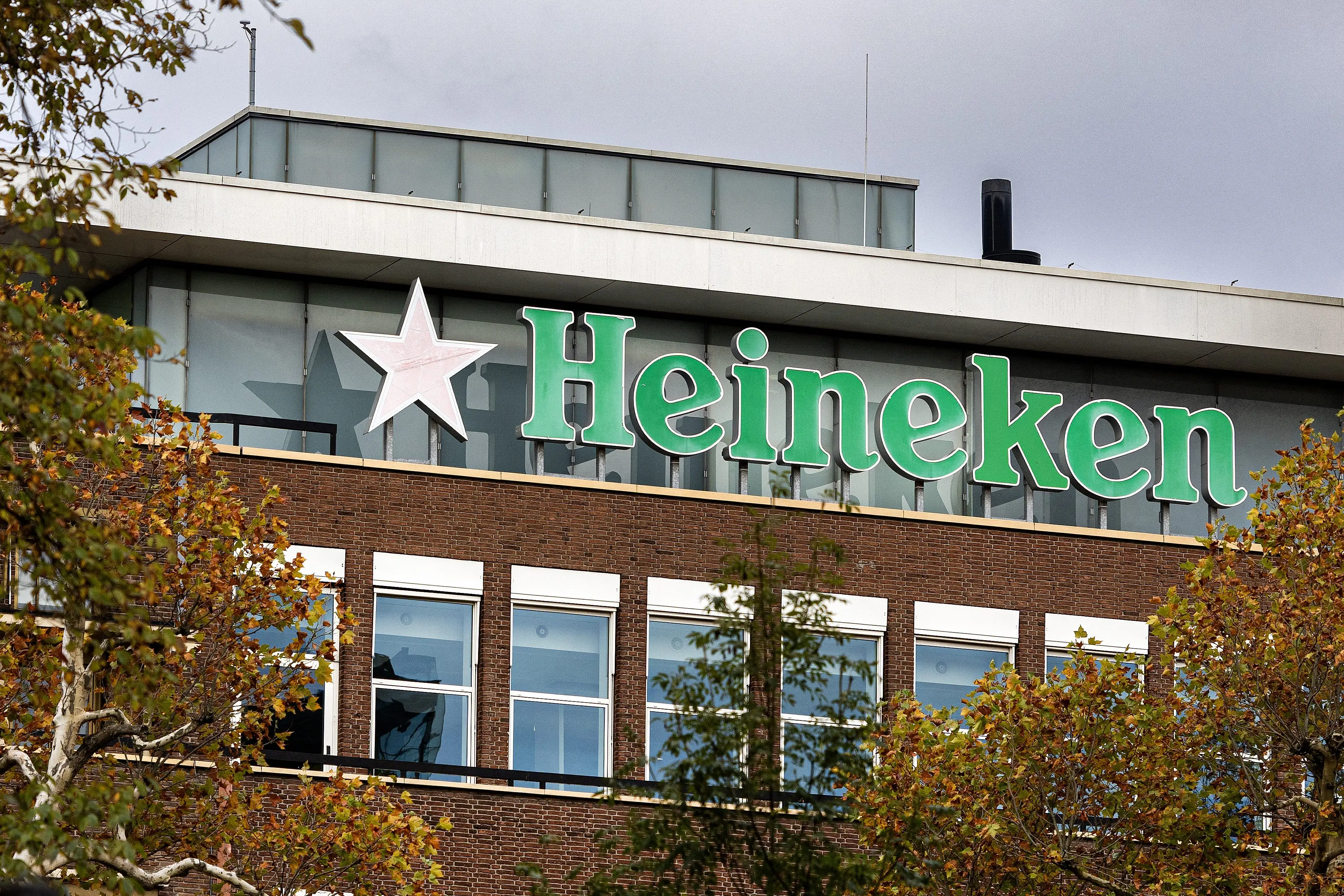 Heineken logo on building with autumnal trees in front of it.