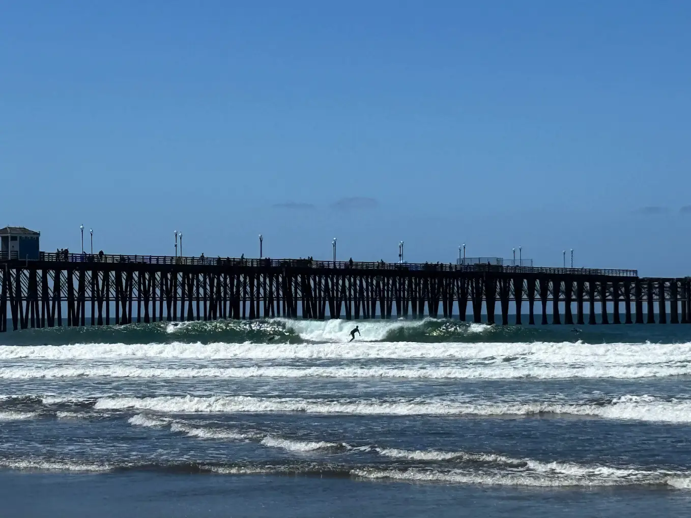 A shot of a person surfing a wave at the beach in Oceanside, California.