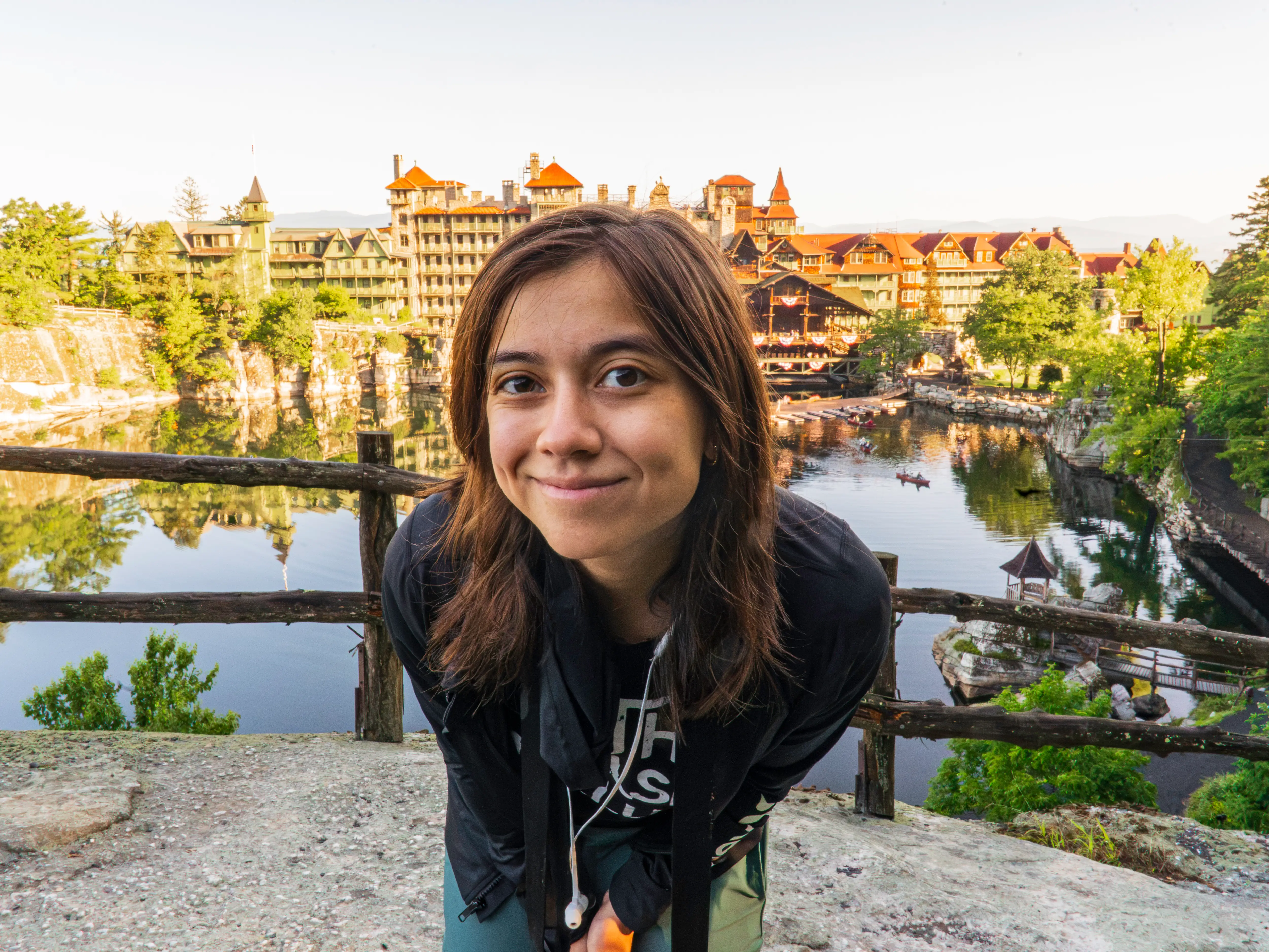The author stands on a scenic overlook above a lake and historic resort buildings at Mohonk Mountain House