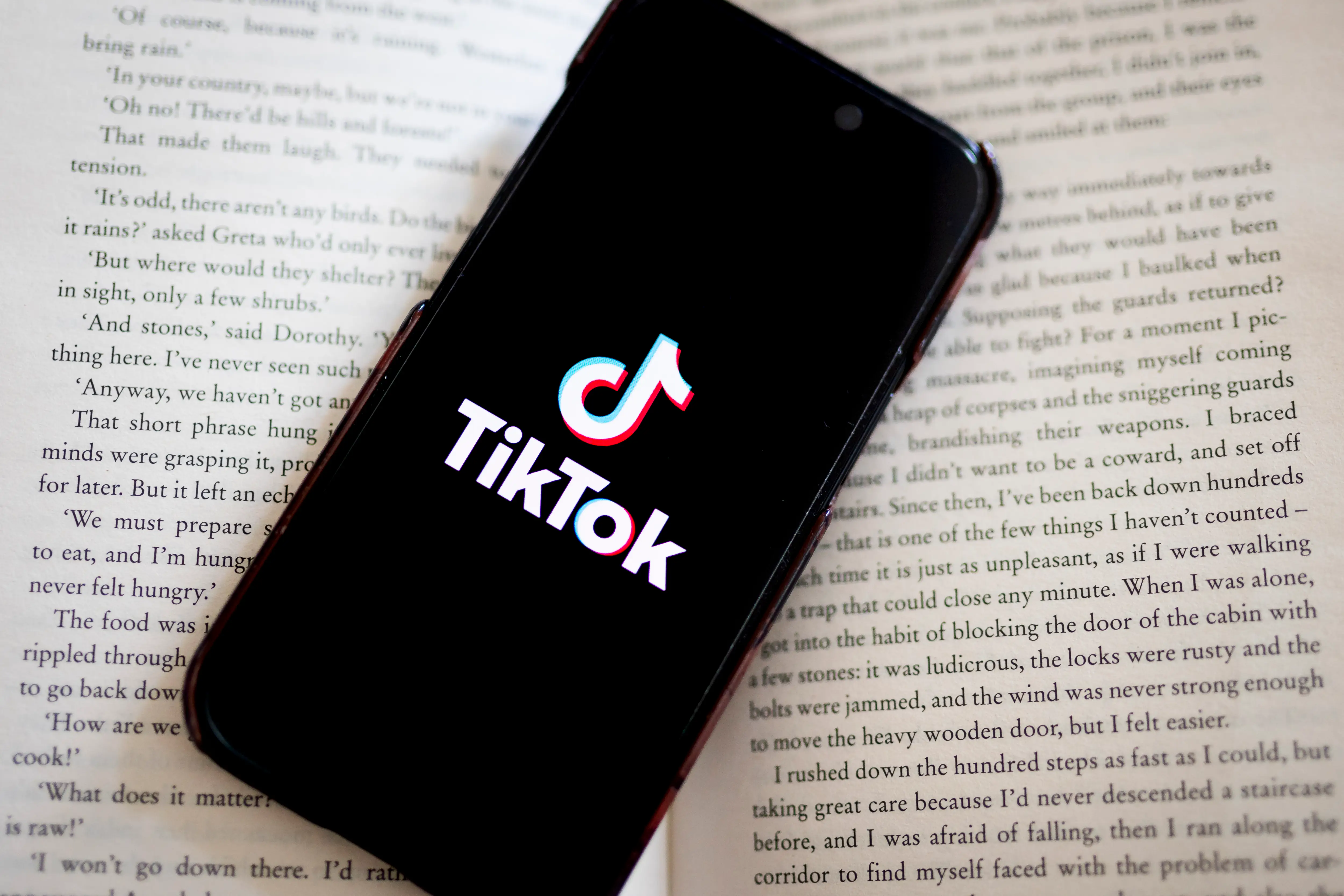 A phone with the logo of the TikTok app lies on an open book