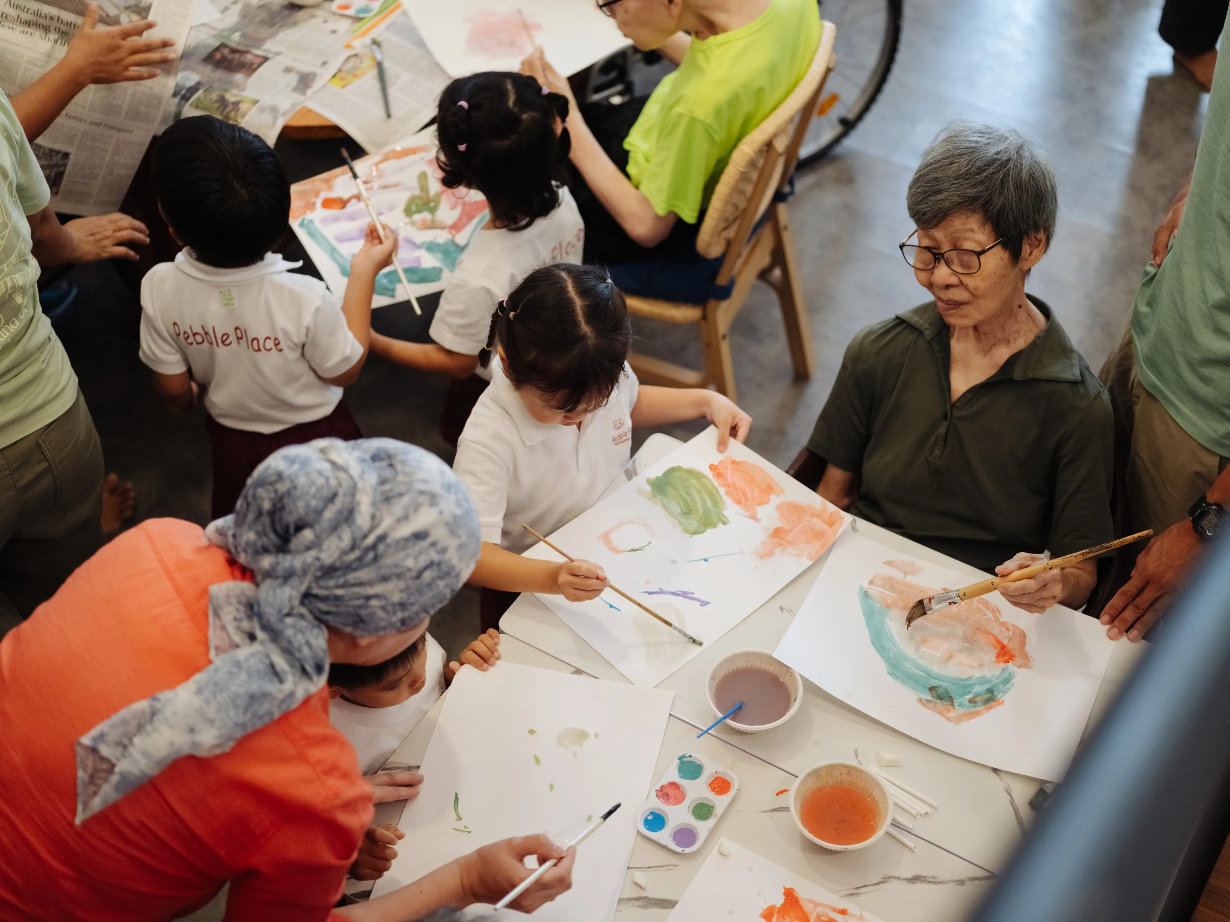 Kids and a volunteer painting with an older resident of Camino House.